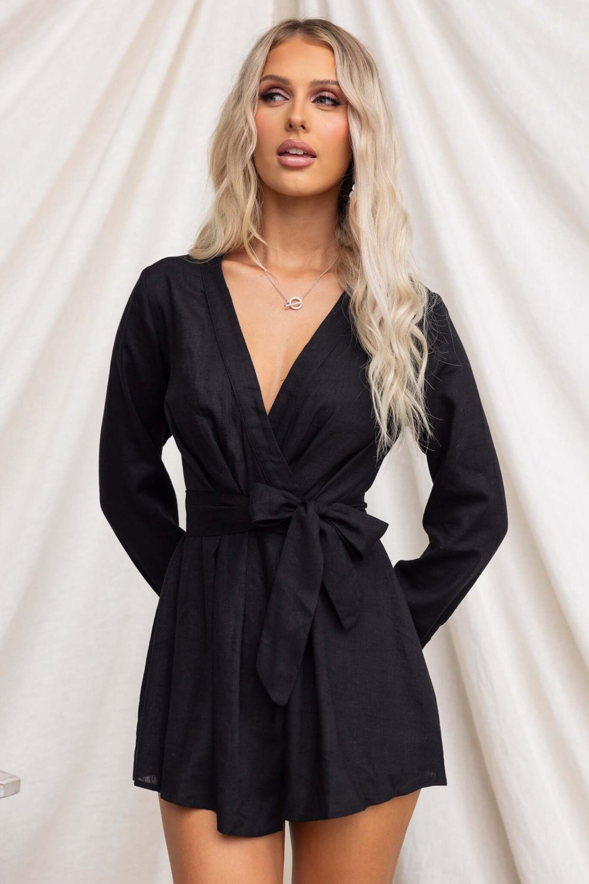 Black Hosier Playsuit with V-neckline and removable tie, featuring long sleeves and a stylish design.