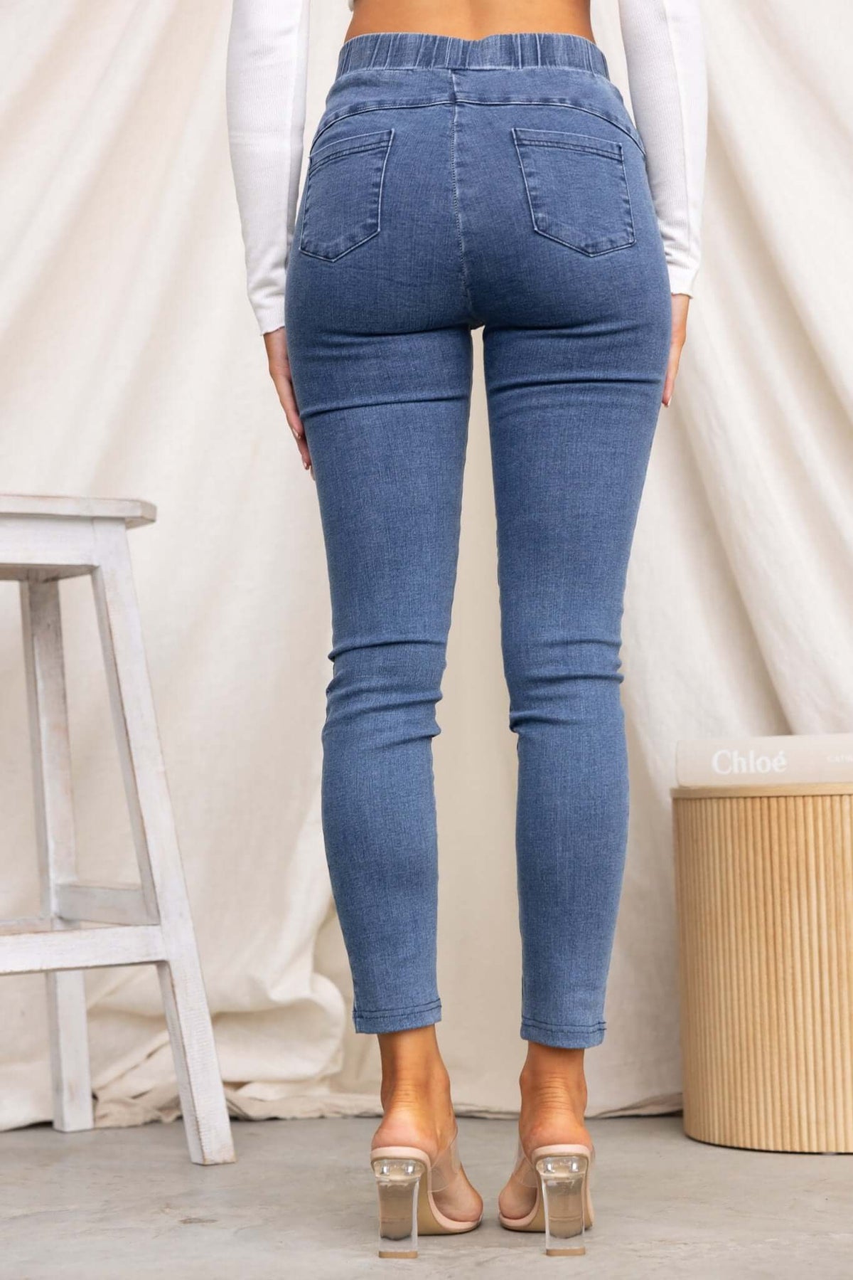 Back view of Durant Jeans featuring mid-high waist, elastic waistband, and back pockets, styled with casual heels.