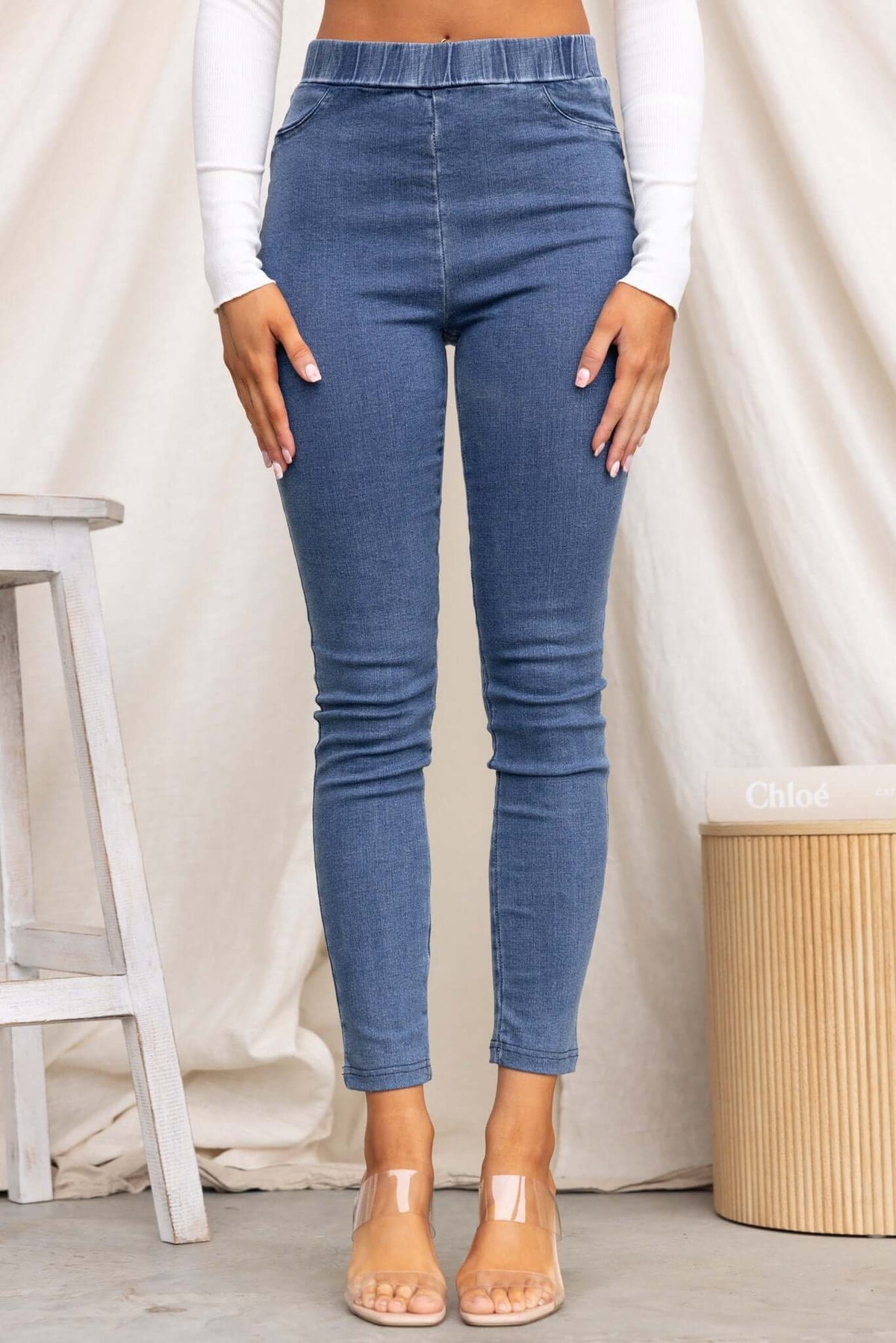 Model wearing Durant Jeans, a high-waisted denim jegging with a stretchy waistband and back pockets.