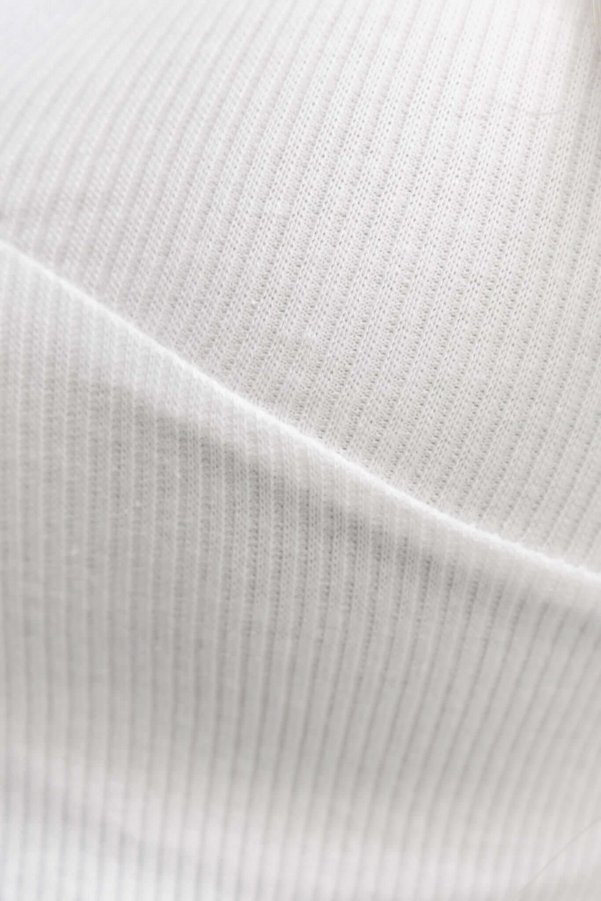 Close-up of white ribbed fabric showcasing its texture, perfect for the Akron Top's stylish V-neckline.