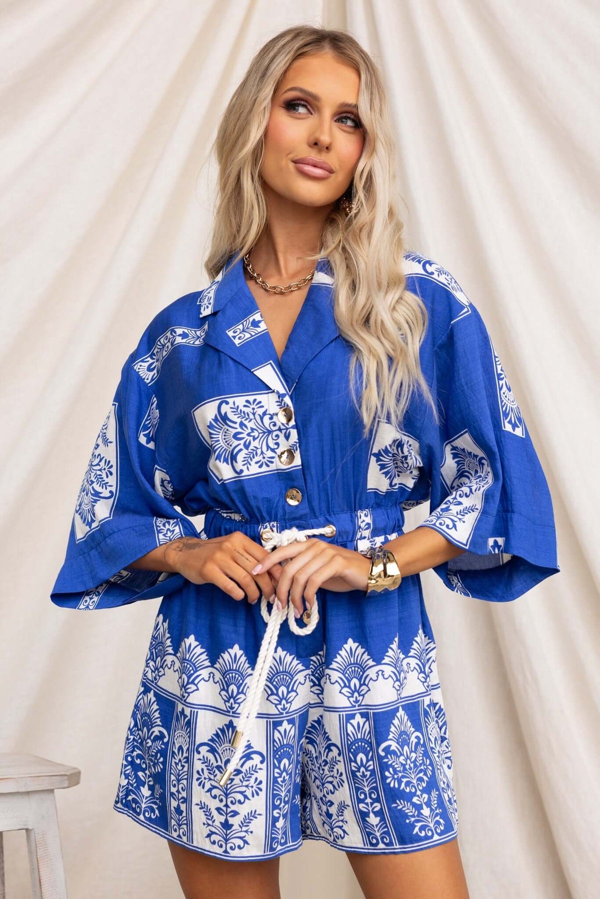 Model wearing a blue and white Fiddler Playsuit featuring a collar, button-up front, and elastic waistband with drawstring.