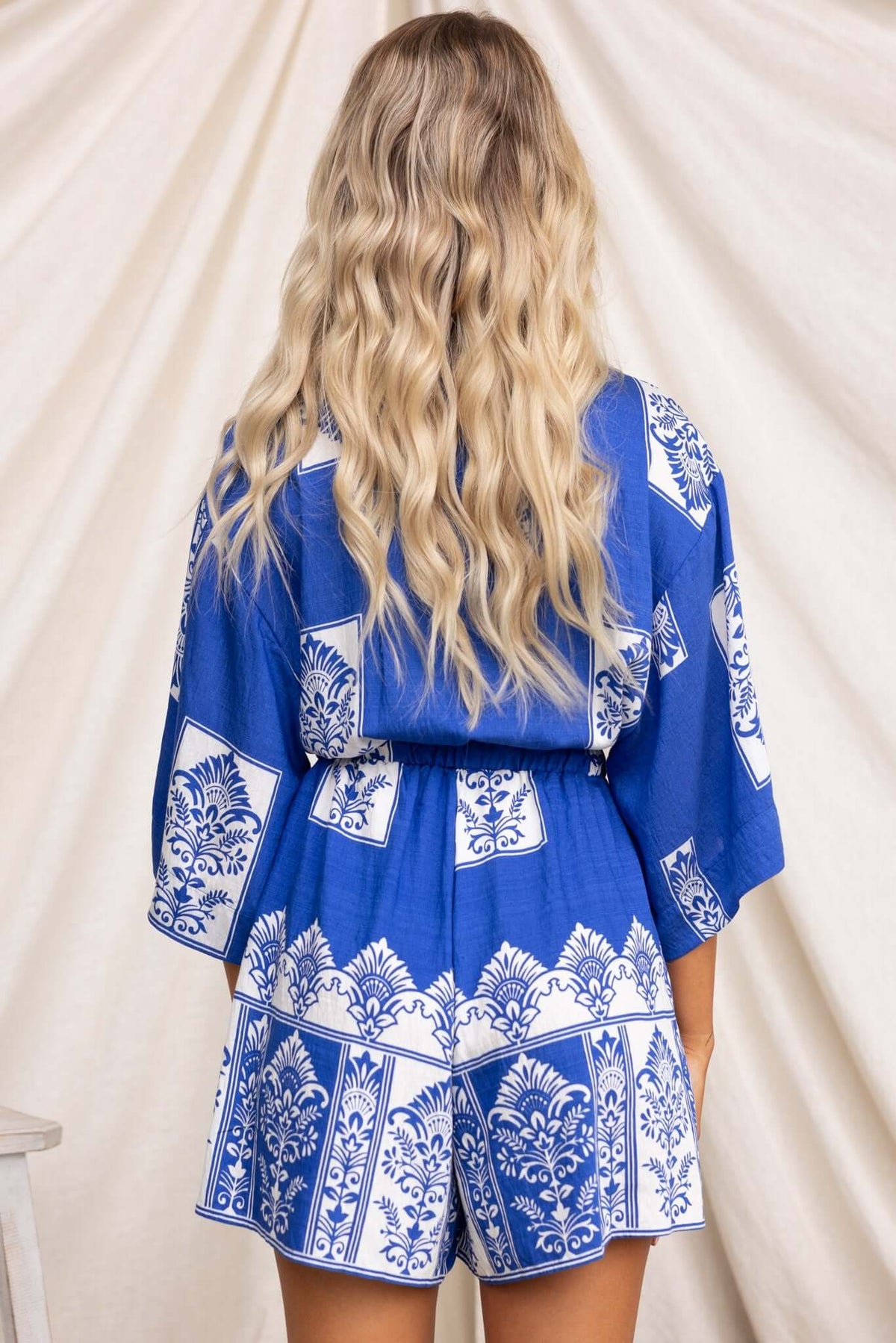 Back view of a Fiddler Playsuit in blue with white patterns, featuring a relaxed fit and elastic waistband.