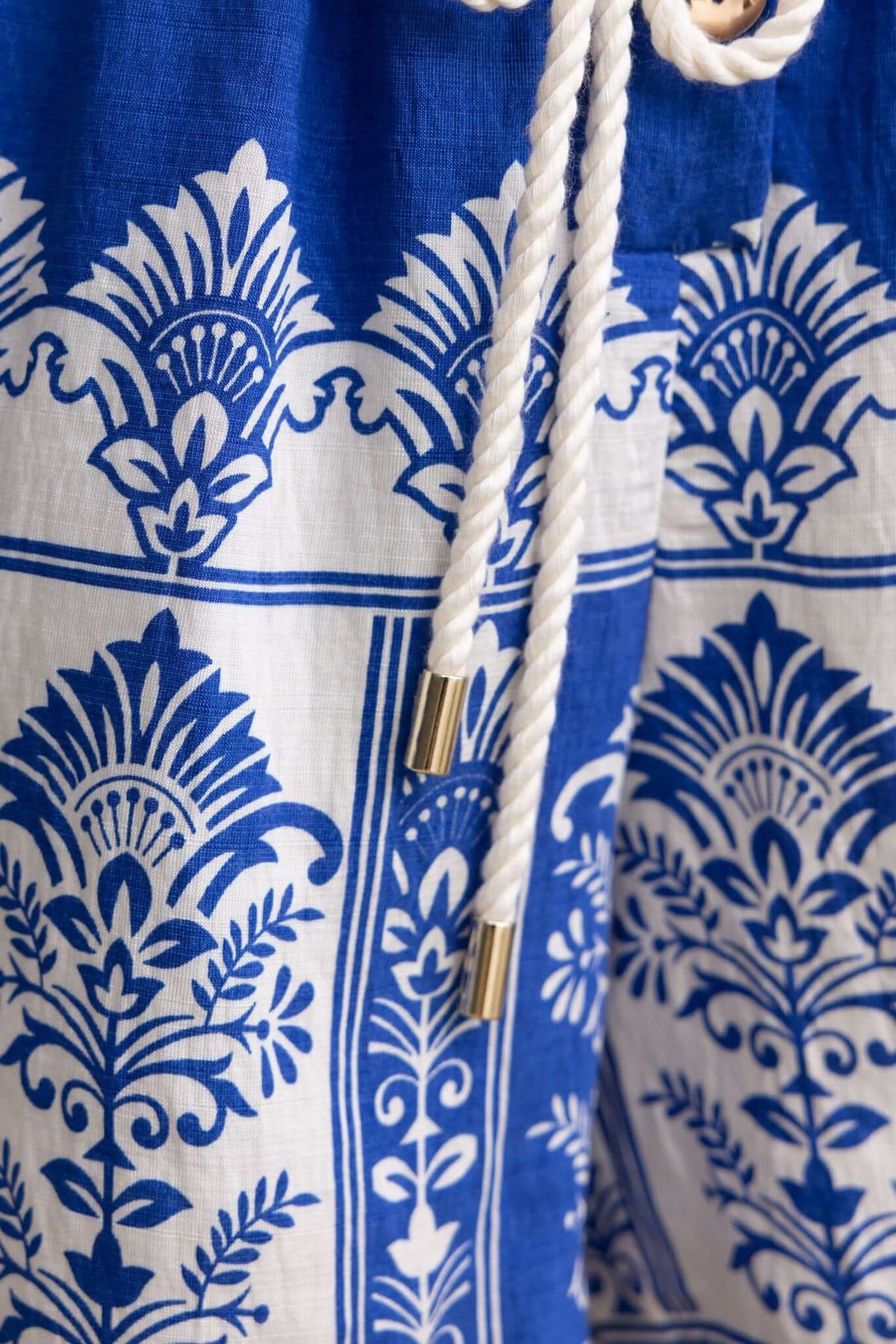 Close-up of blue and white patterned fabric with drawstring and button details from the Fiddler Playsuit.