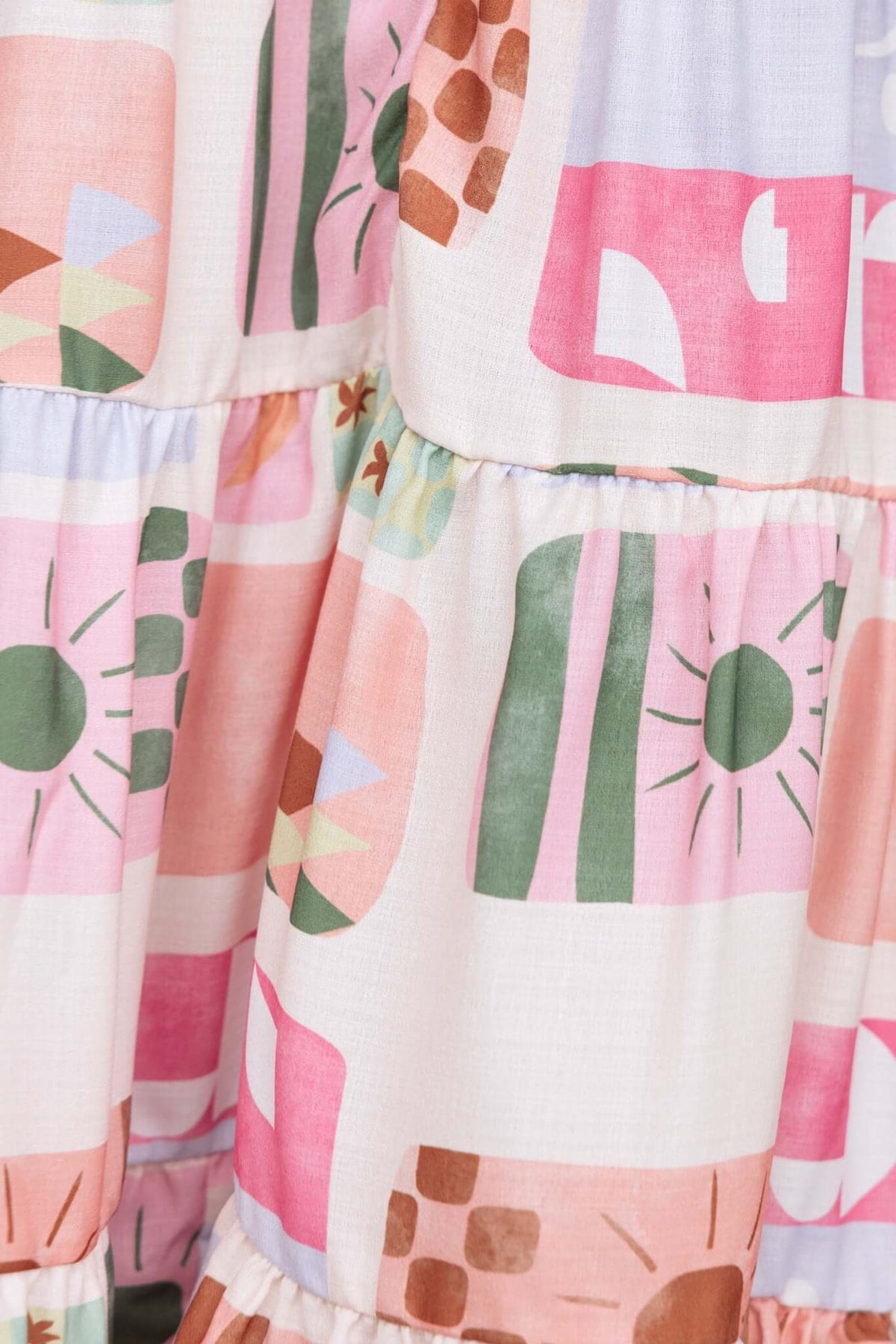 Close-up of the patterned fabric of the Mariella Dress featuring pink, green, and geometric designs.