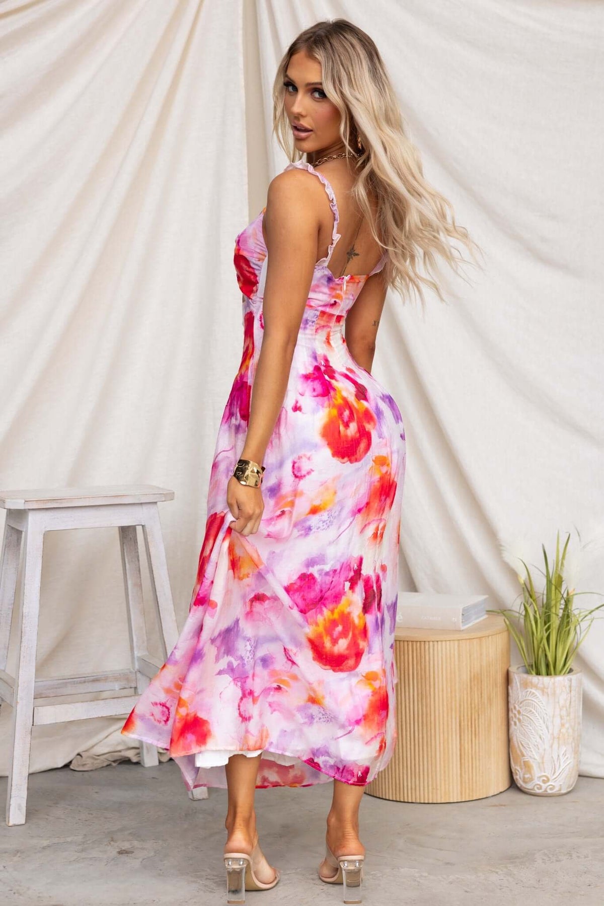 Estelle Midi Dress featuring a colorful floral pattern, elastic straps, and a cut-out waist, showcased on a model.