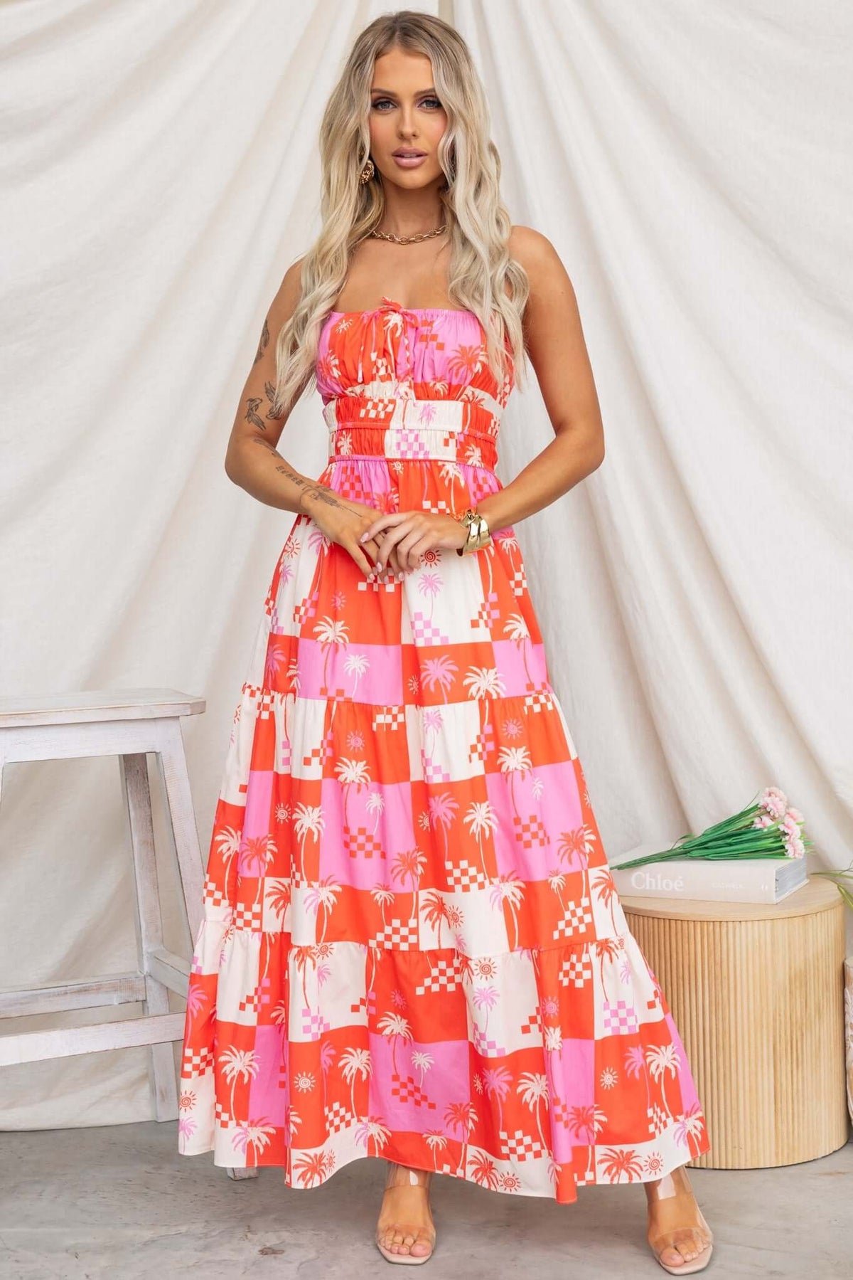Model wearing a vibrant Norment maxi dress featuring adjustable straps and a tie detail at the front.