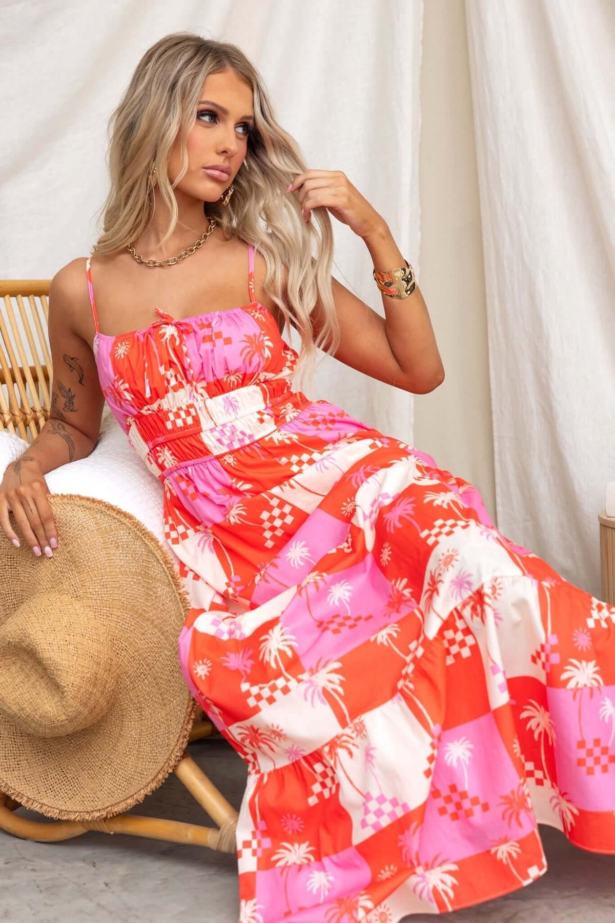 Model wearing Norment Maxi Dress with thin straps and tie detail, a vibrant tropical print against a soft backdrop.
