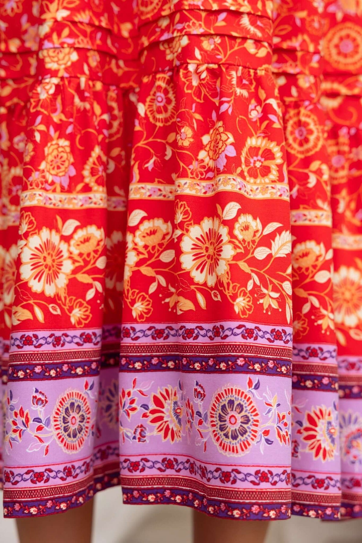 Close-up of Skipper Midi Dress fabric featuring vibrant floral patterns in red, orange, and purple hues.