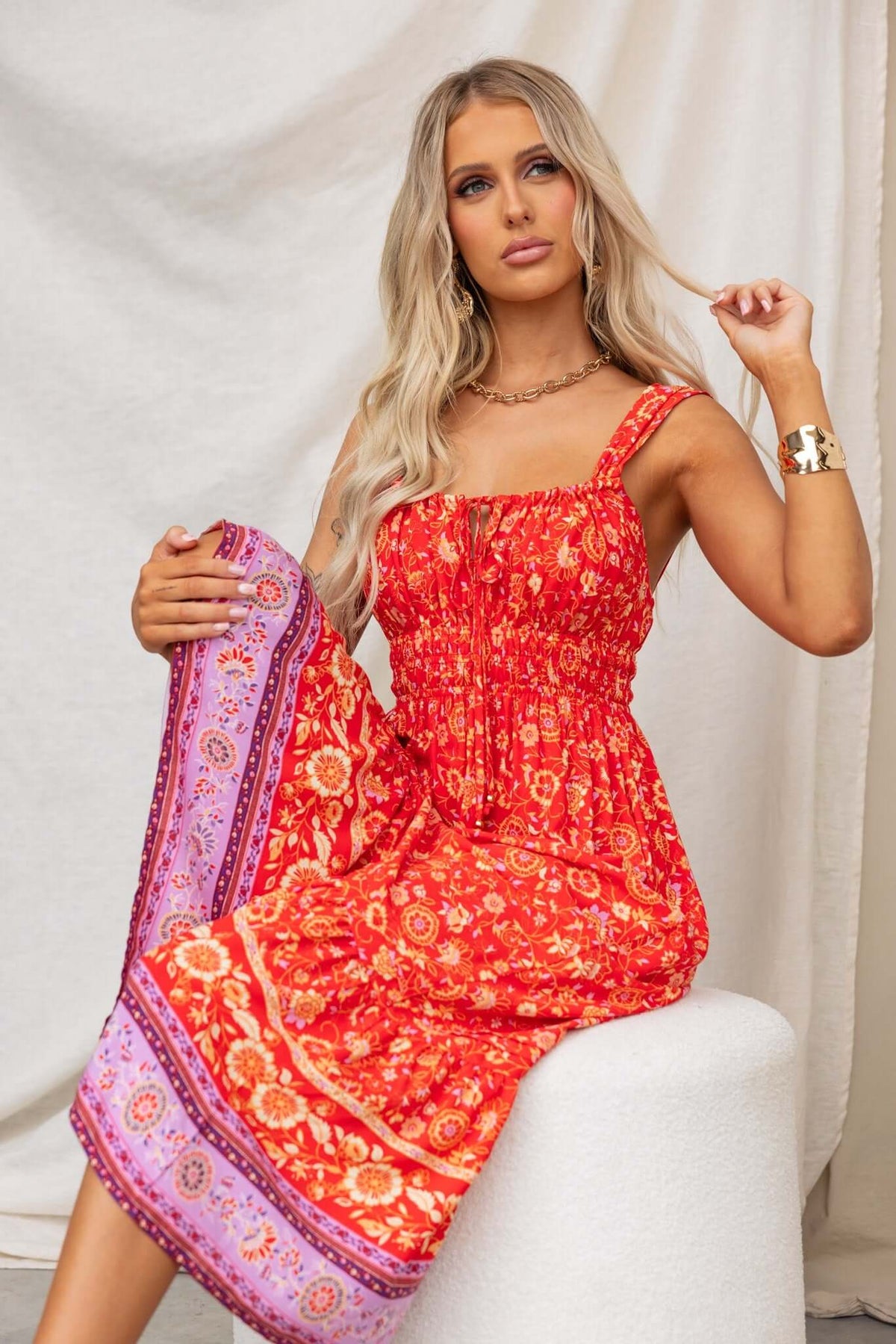 Model wearing Skipper Midi Dress in vibrant red floral print with adjustable straps and elastic waist.