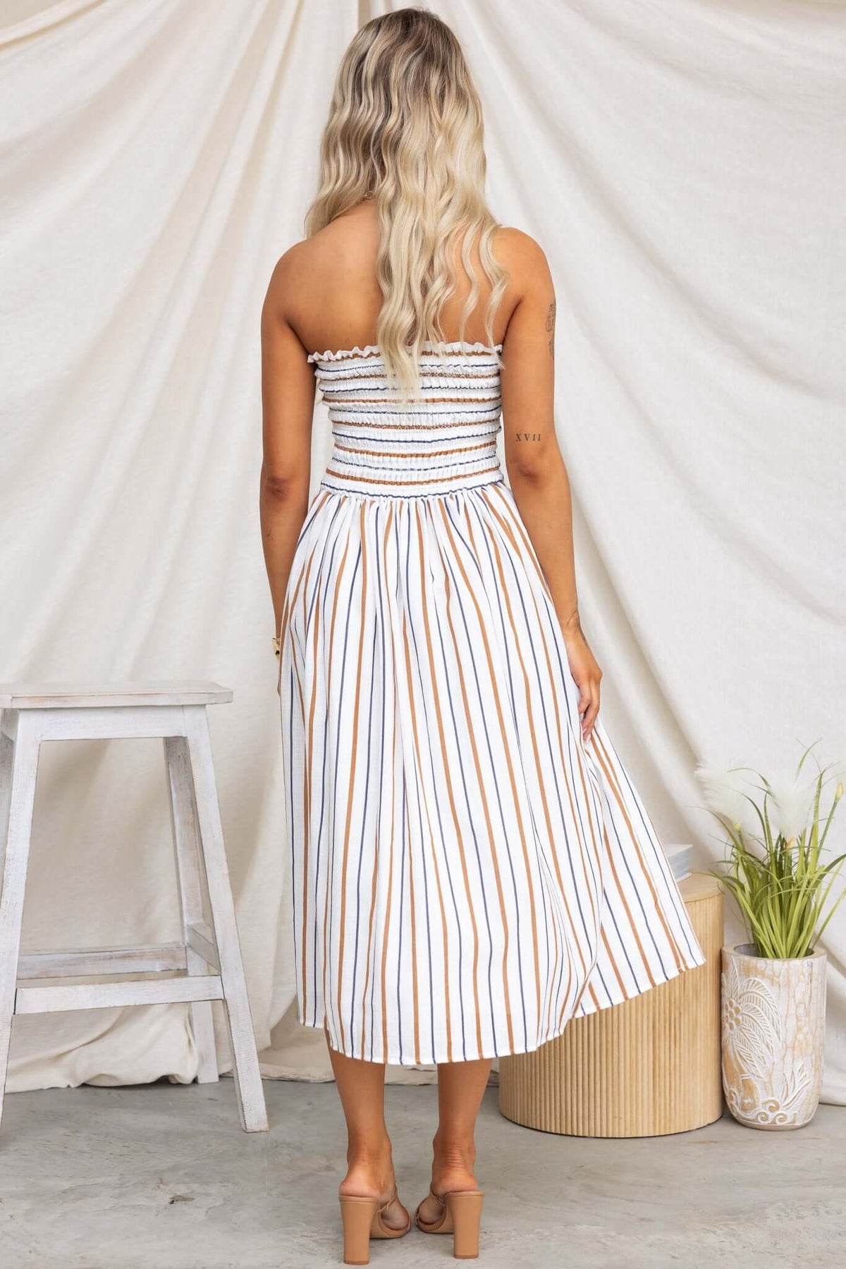 Back view of Elkie Midi Dress, a strapless cotton dress with a smocked bodice and striped pattern, perfect for summer wear.