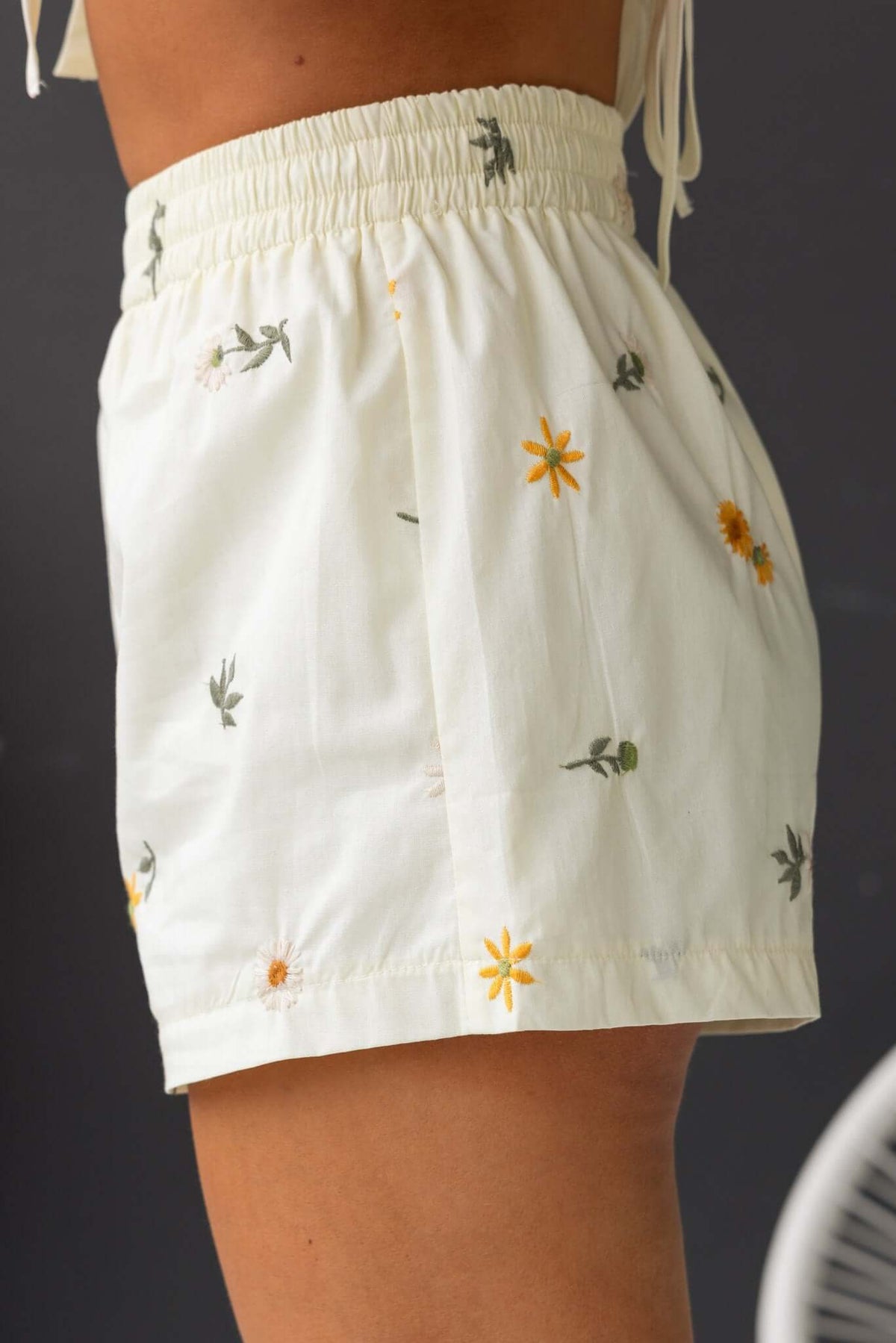 Side view of Tori Shorts featuring a mid-high waist, elastic waistband, and floral embroidery on soft cotton fabric.