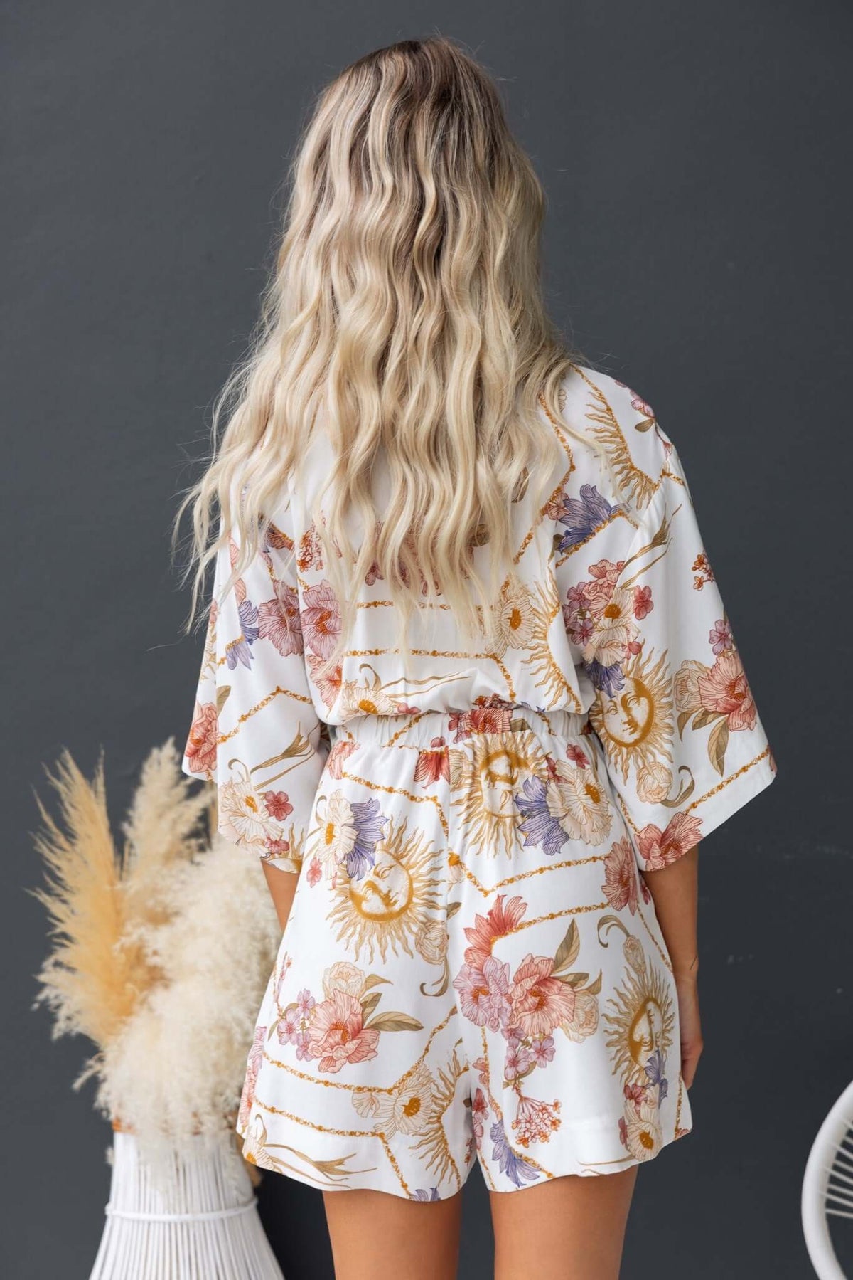 Back view of a Fiddler Playsuit featuring floral print, relaxed fit, elastic waistband, and short sleeves.