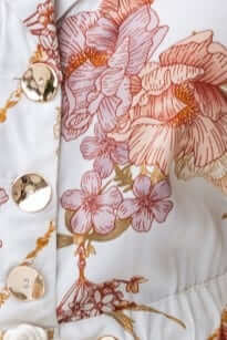 Close-up of the floral pattern and button detail on the Fiddler Playsuit, showcasing its elegant design.