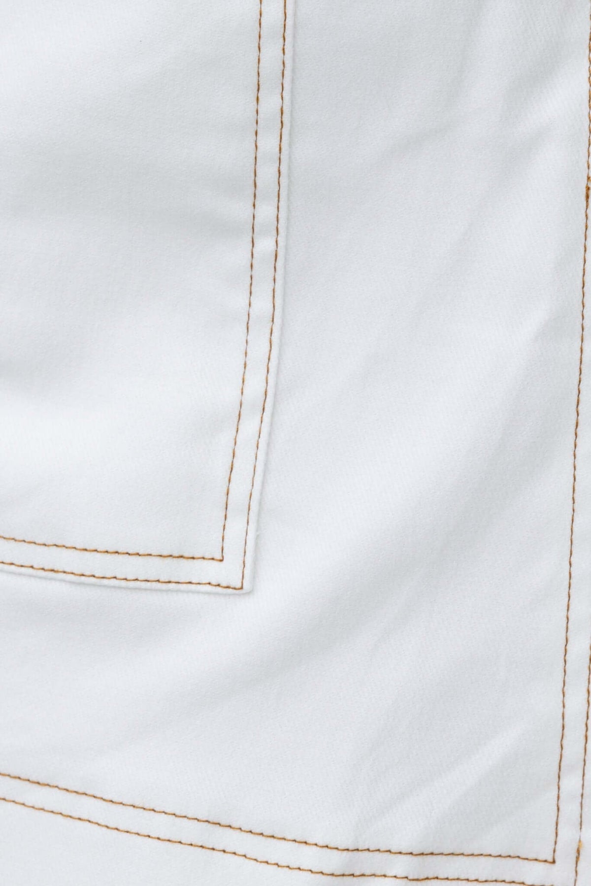 Close-up of white fabric with contrasting stitching, showcasing detailed seams and texture for Tink Denim Shorts.