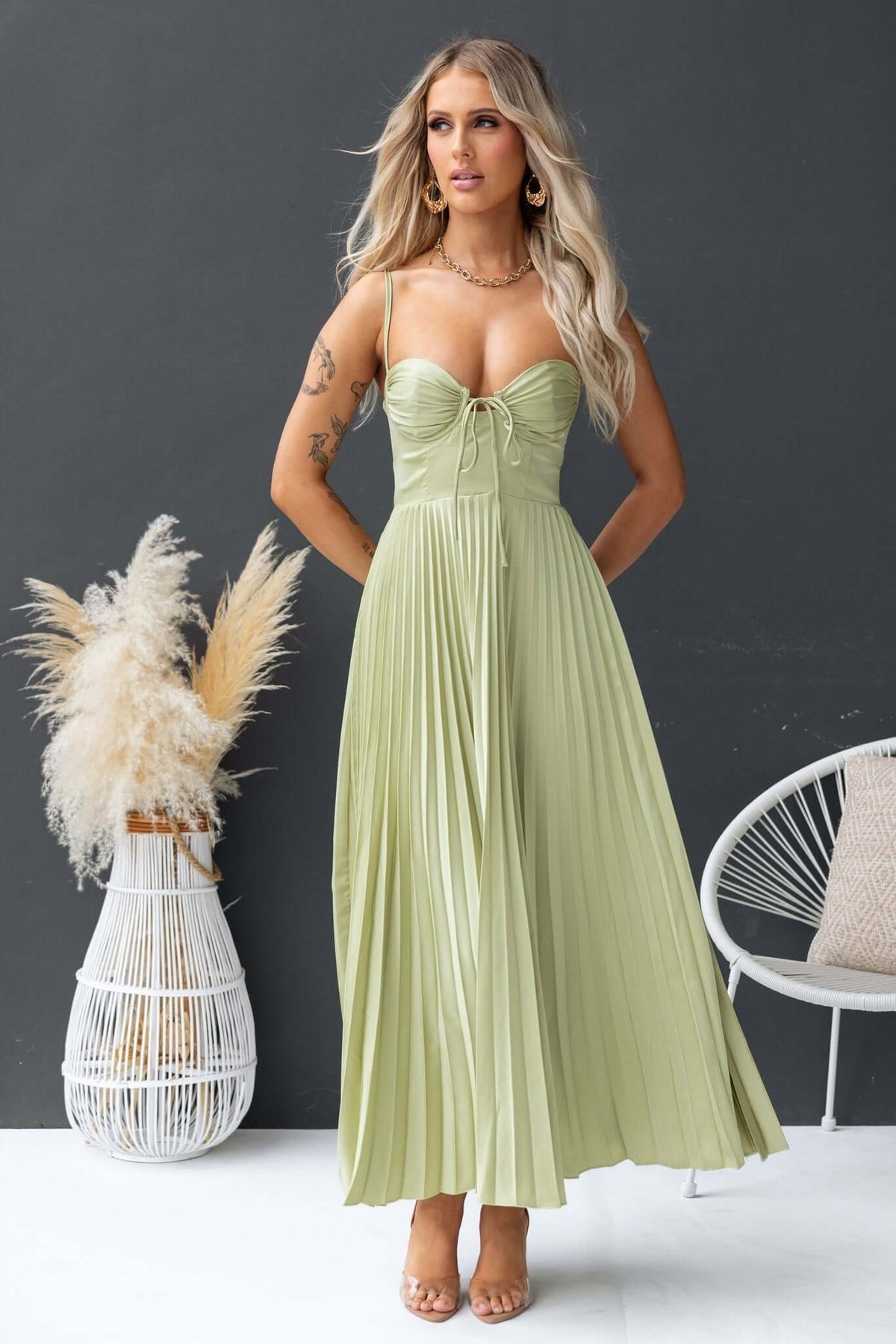 Danette Maxi Dress in light green with pleated skirt and adjustable straps, styled with natural accessories.