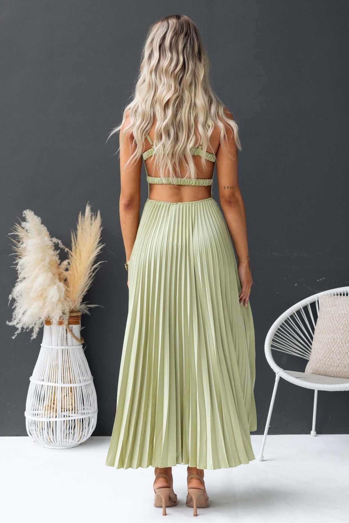 Back view of a model wearing a pleated Danette Maxi Dress in light green with adjustable straps and a stylish fit.