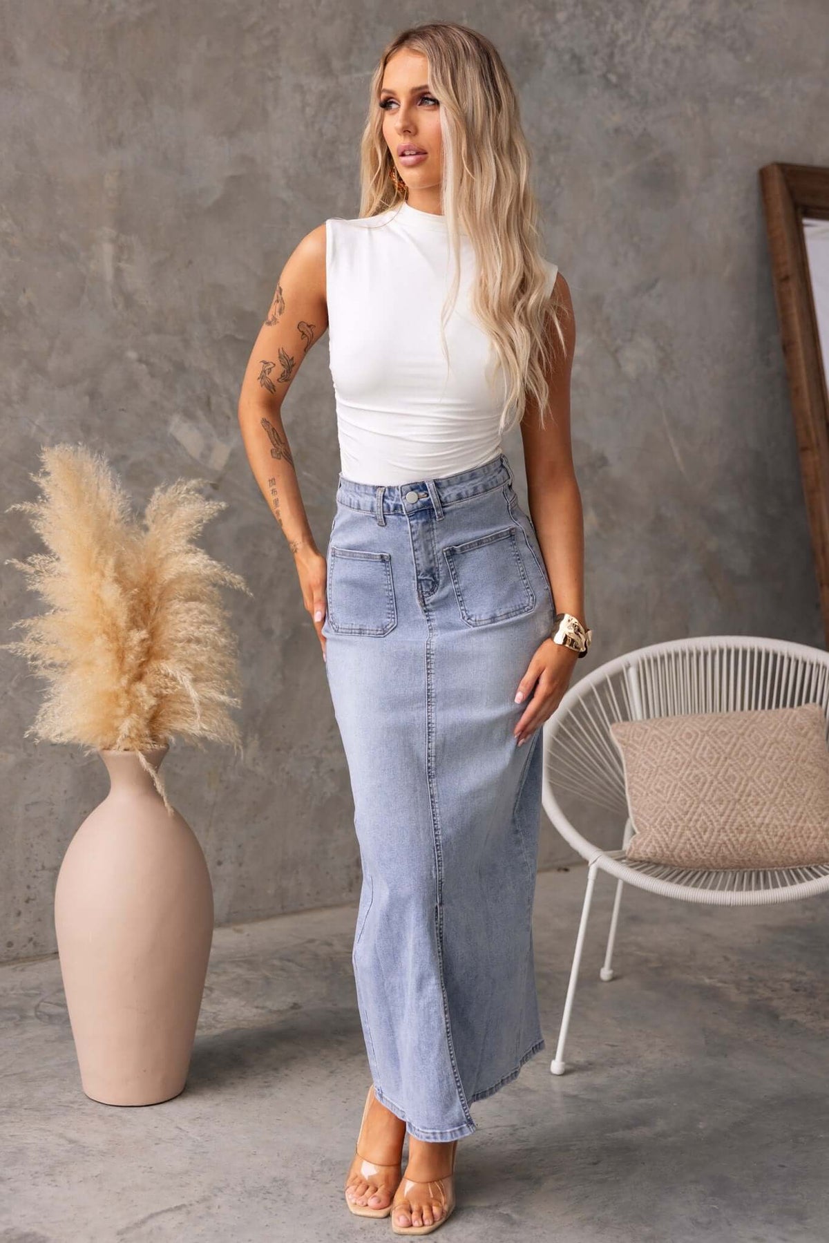 Model wearing a Naomi Denim Maxi Skirt with a mid-high waist, front pockets, and a stylish split, complemented by a white top.
