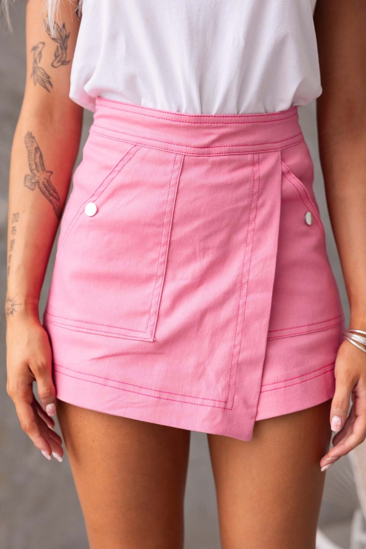 Stylish pink denim skort featuring side pockets and a mid-high waist fit, ideal for casual summer wear.
