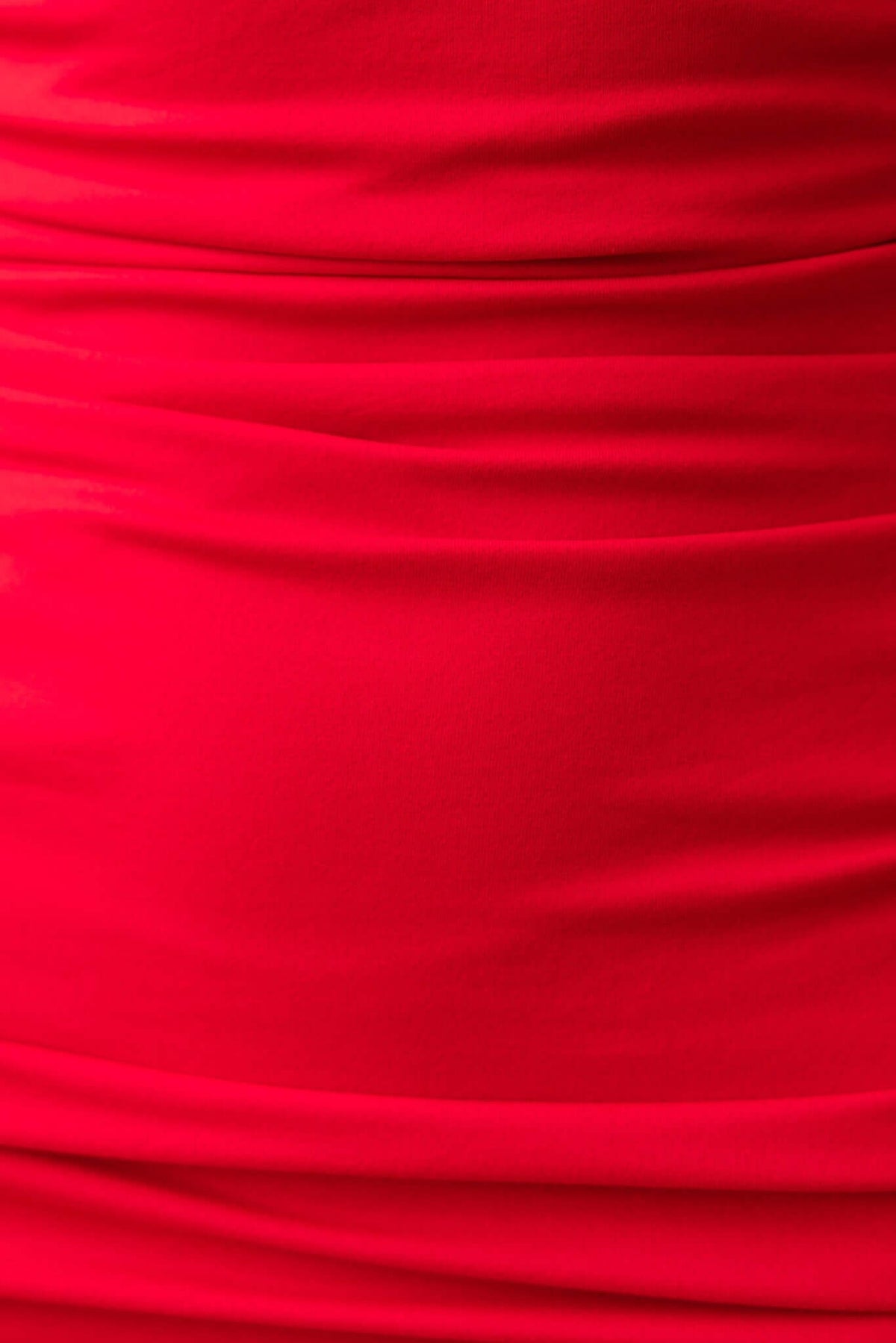 Close-up of red stretch fabric with ruching details, showcasing elegant texture and design for a stylish women’s dress.