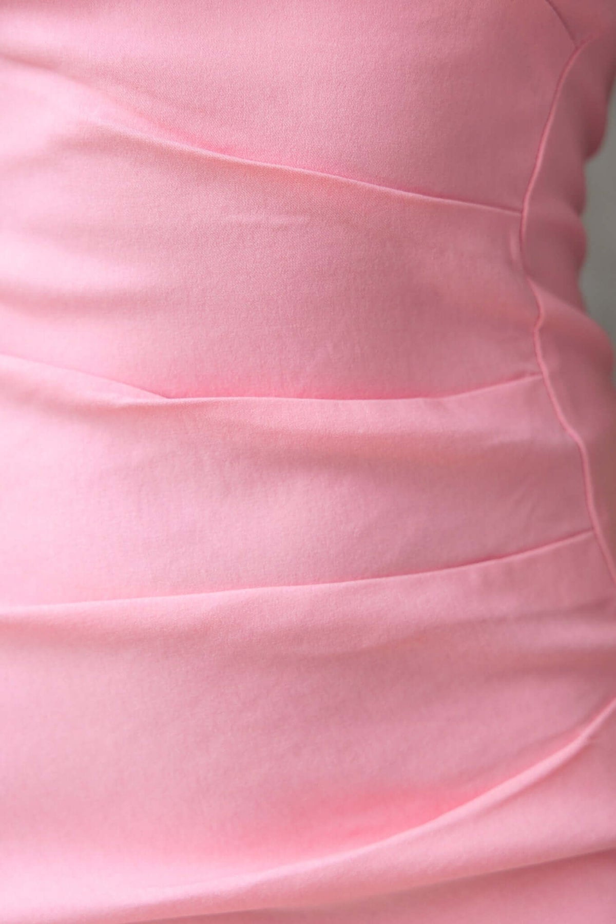 Close-up of the pink fabric of the Ianna Dress, showcasing its soft texture and stylish ruched design.