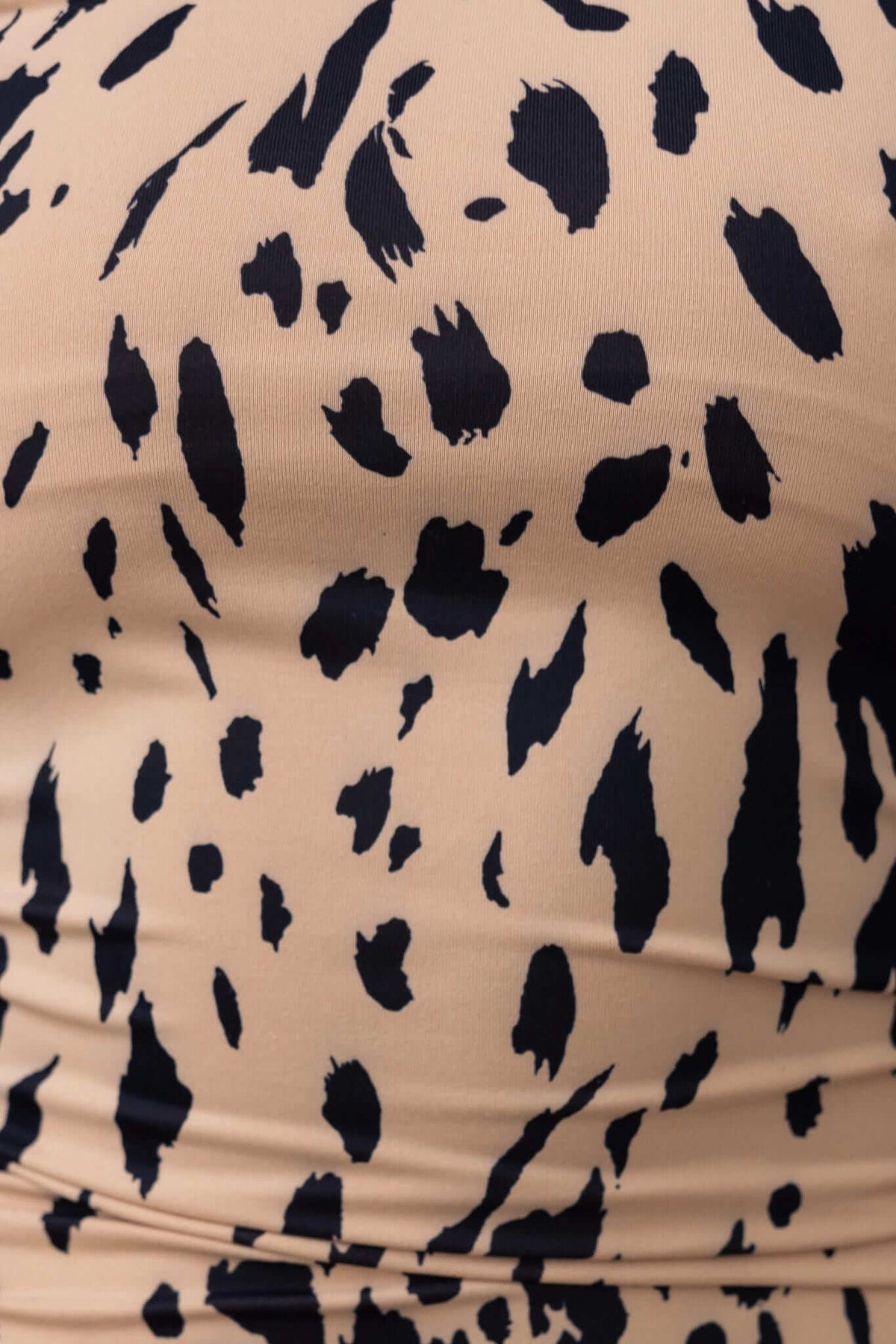Close-up of fabric featuring a leopard print pattern in black on a beige background.