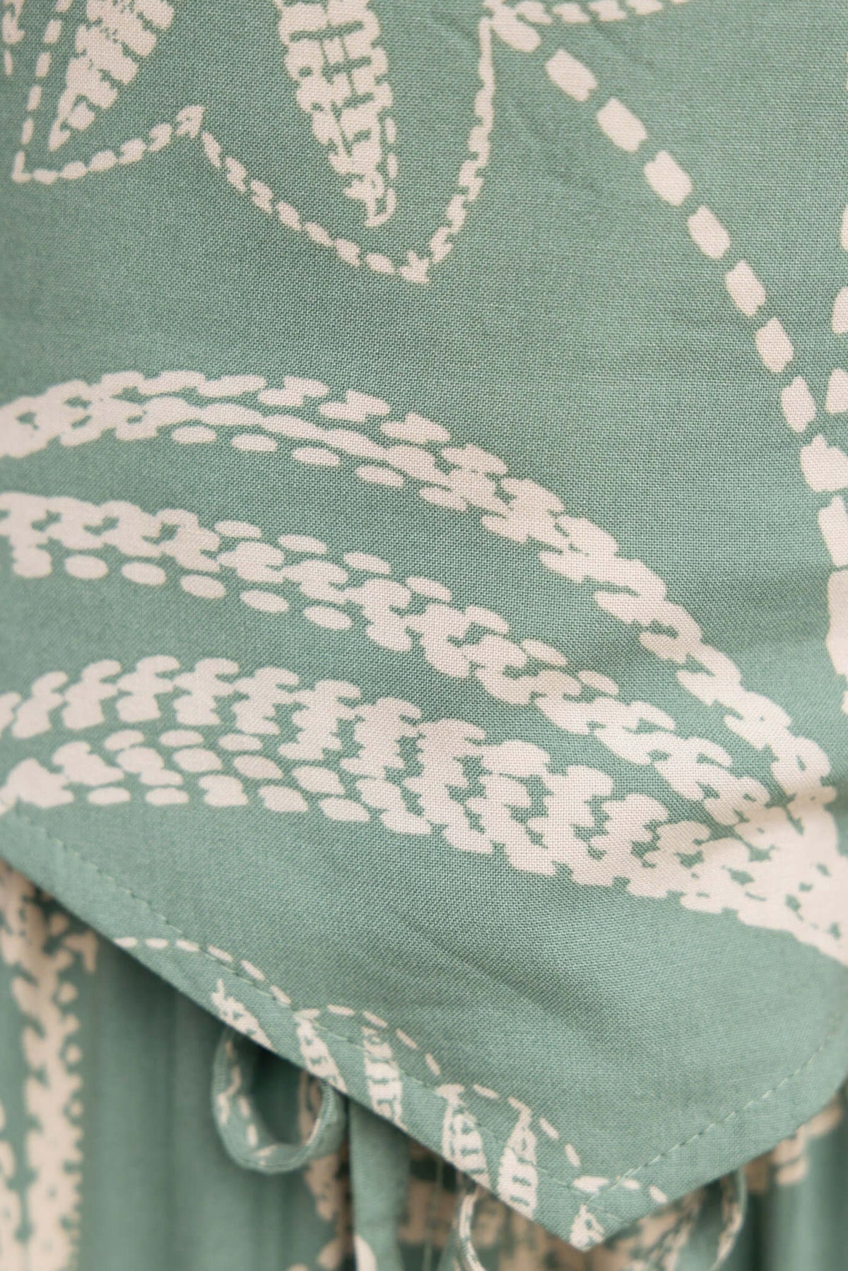 Close-up of green fabric featuring white leaf patterns, showcasing texture and design details.