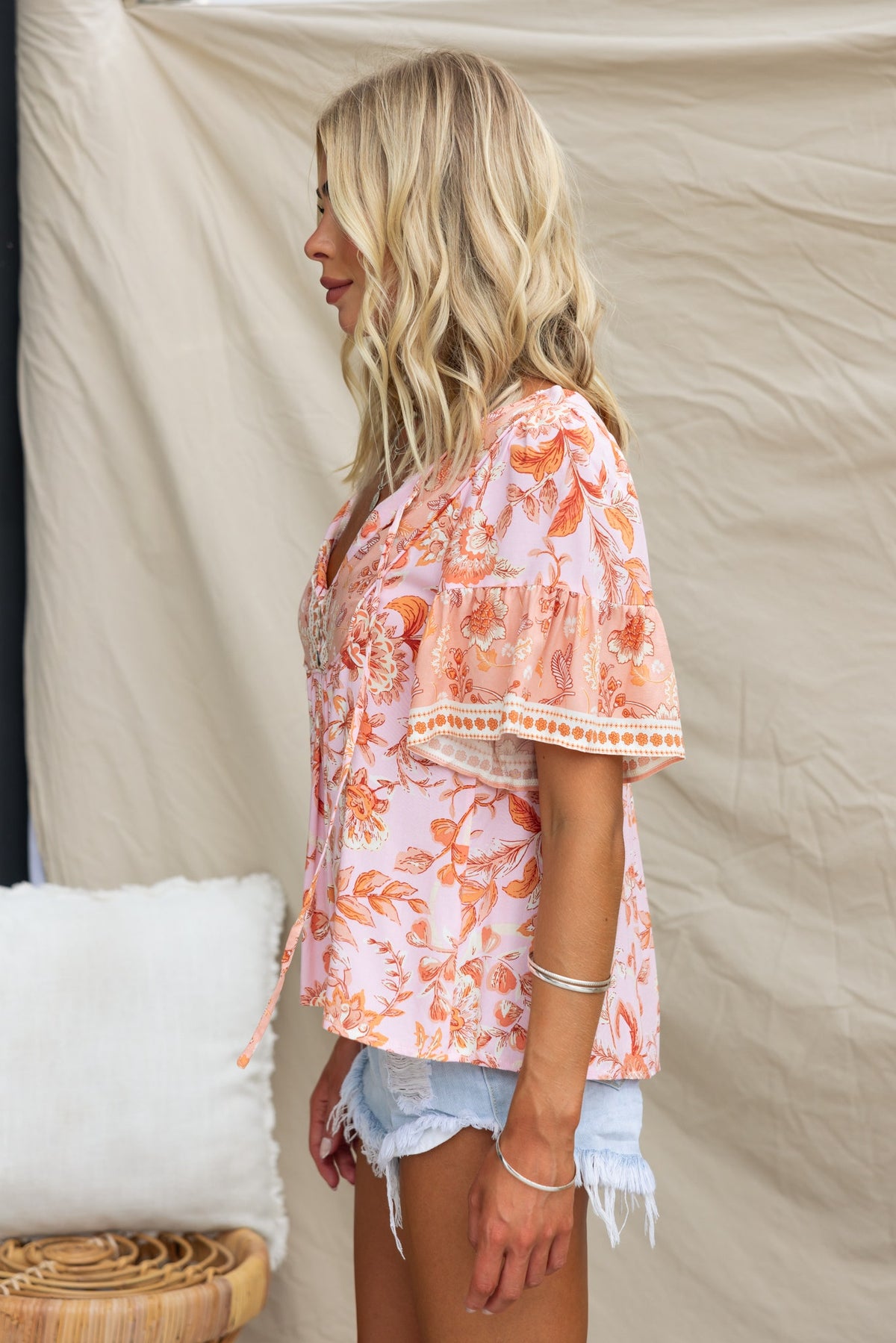 Side view of a model wearing a floral print V-neck Reeva top with tie detail and relaxed fit.