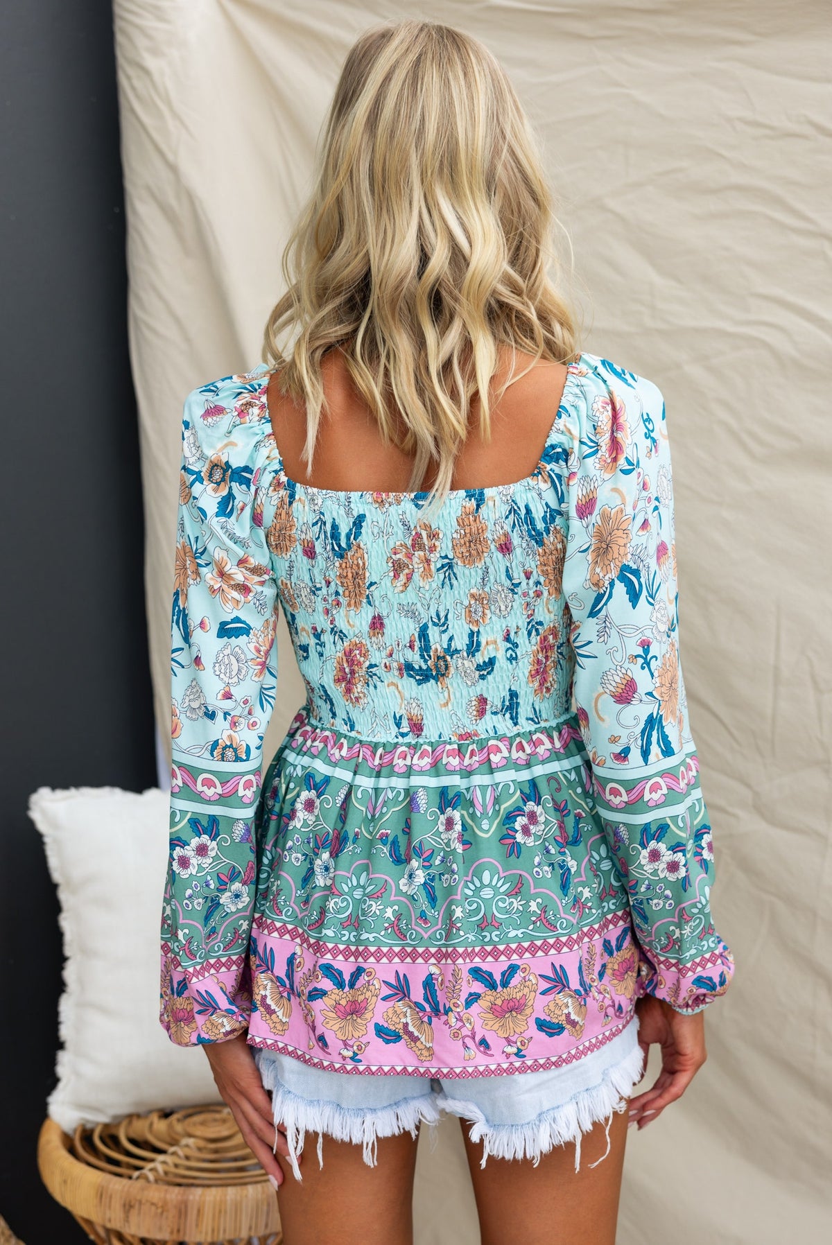 Back view of a floral print Indah top with elastic neckline, paired with white shorts, showcasing colorful design.