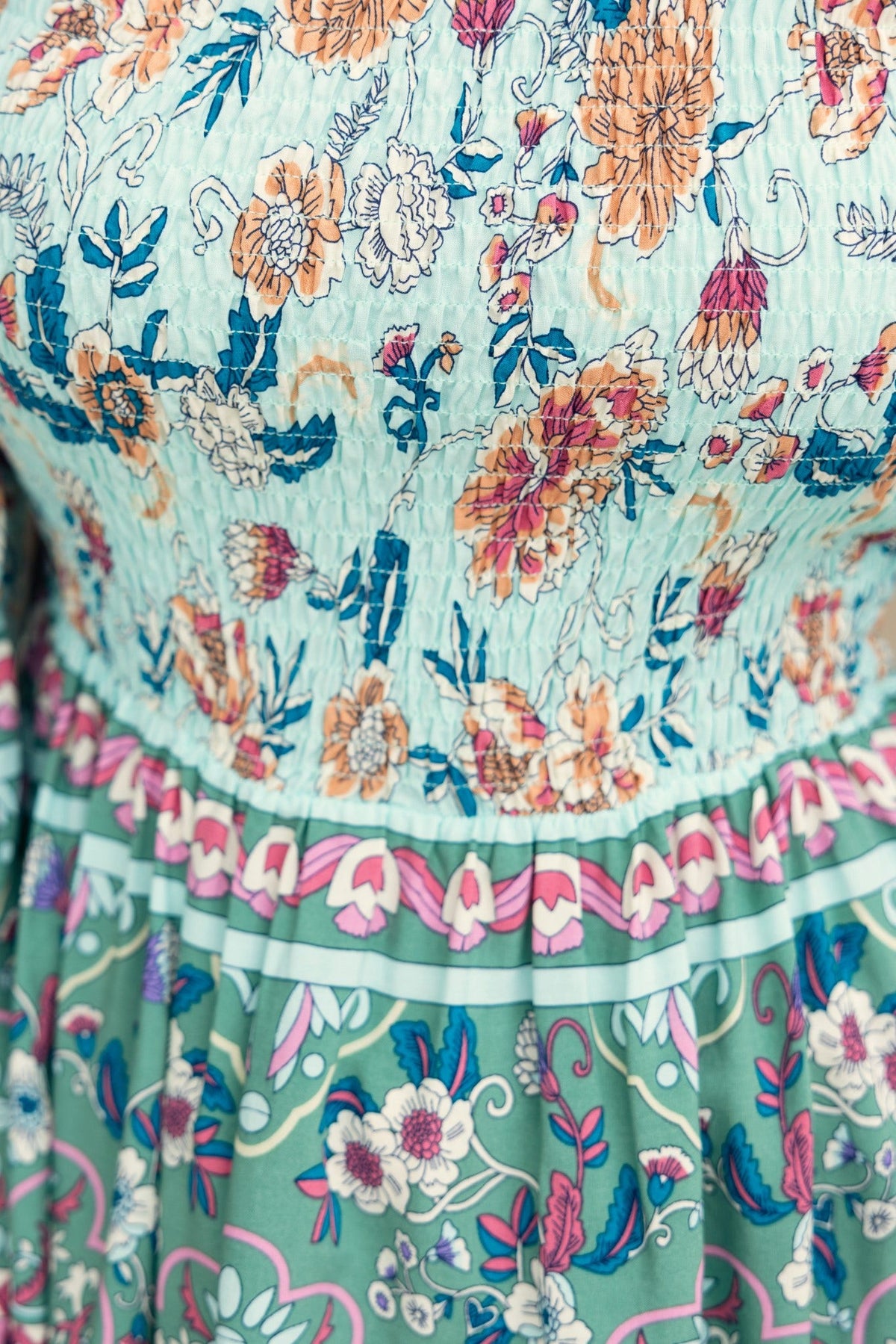 Floral print top highlighting elastic neckline and colorful floral patterns on a light fabric.