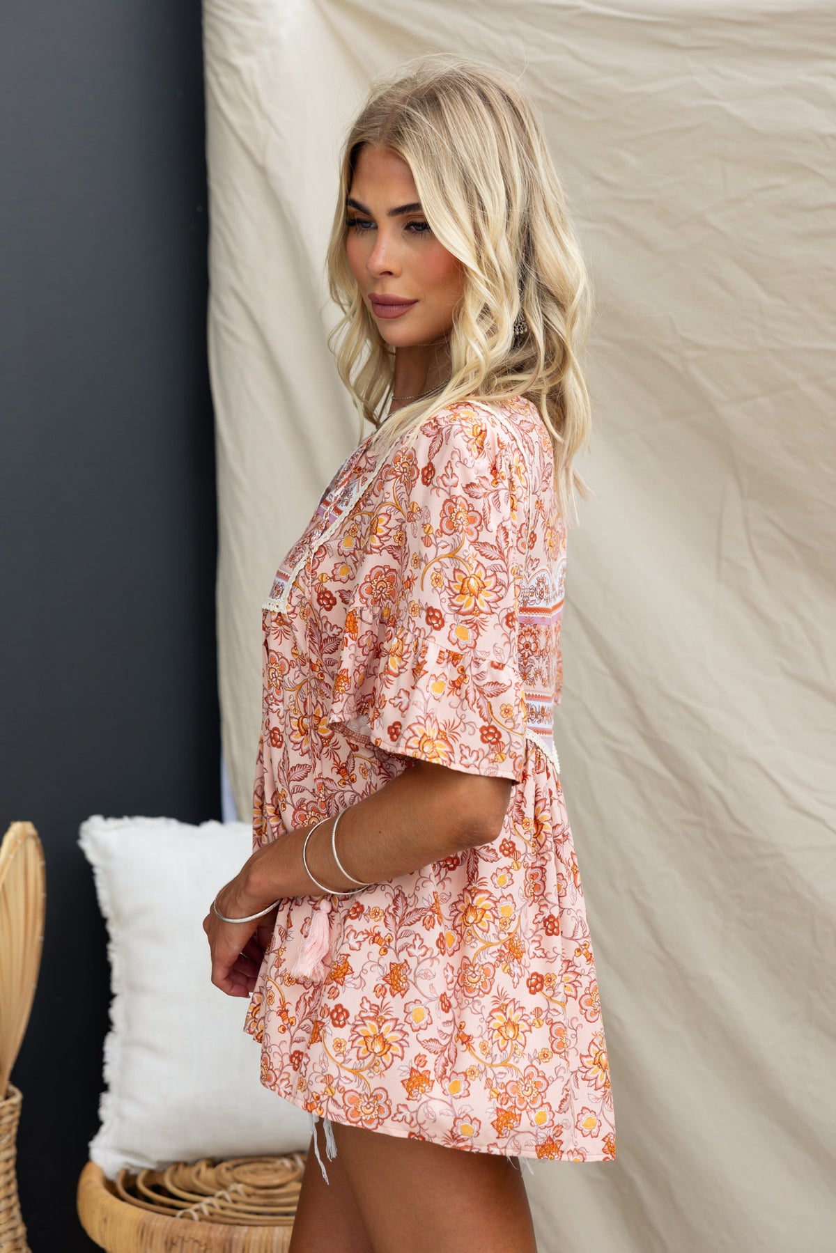 Model wearing the Kyra Top, featuring a floral print, V-neckline, and tie detail, shot against a neutral background.