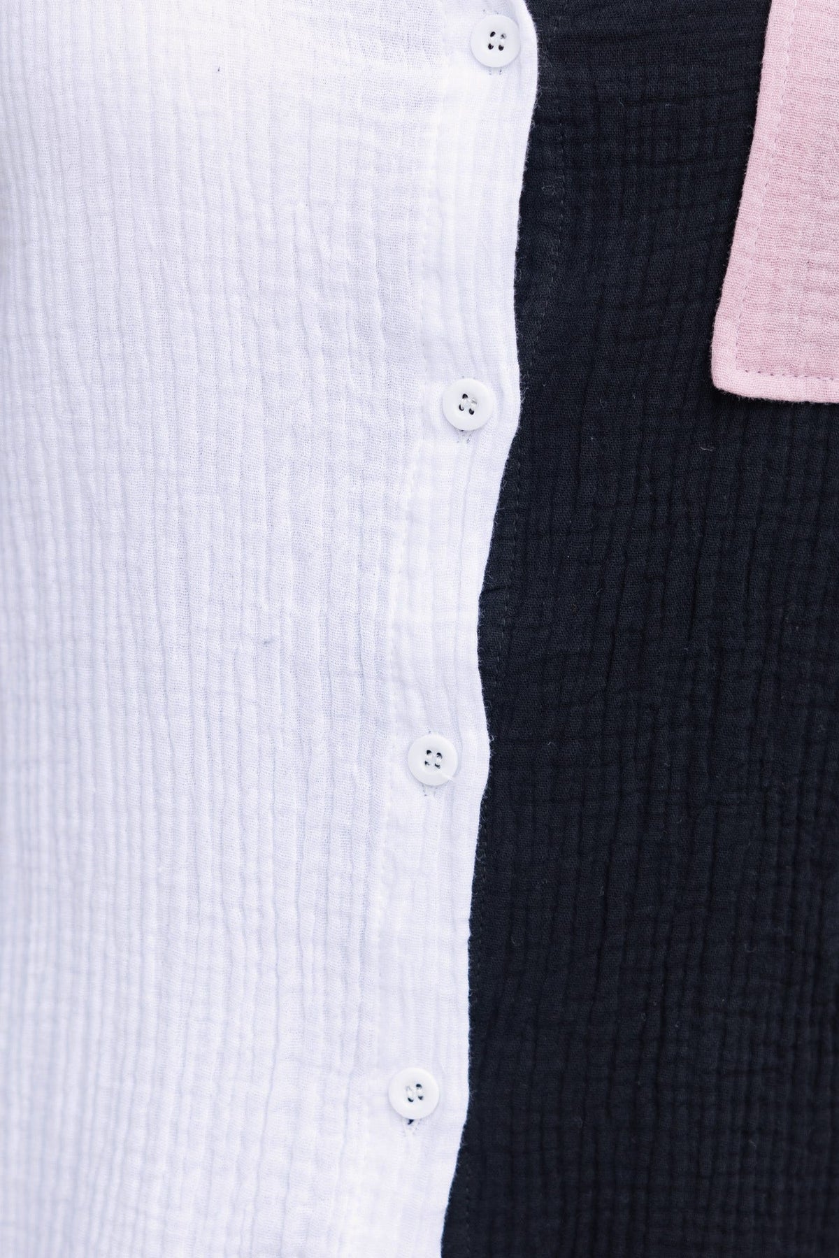 Black and white button-up shirt with textured fabric and pink accent, showcasing the button detail.