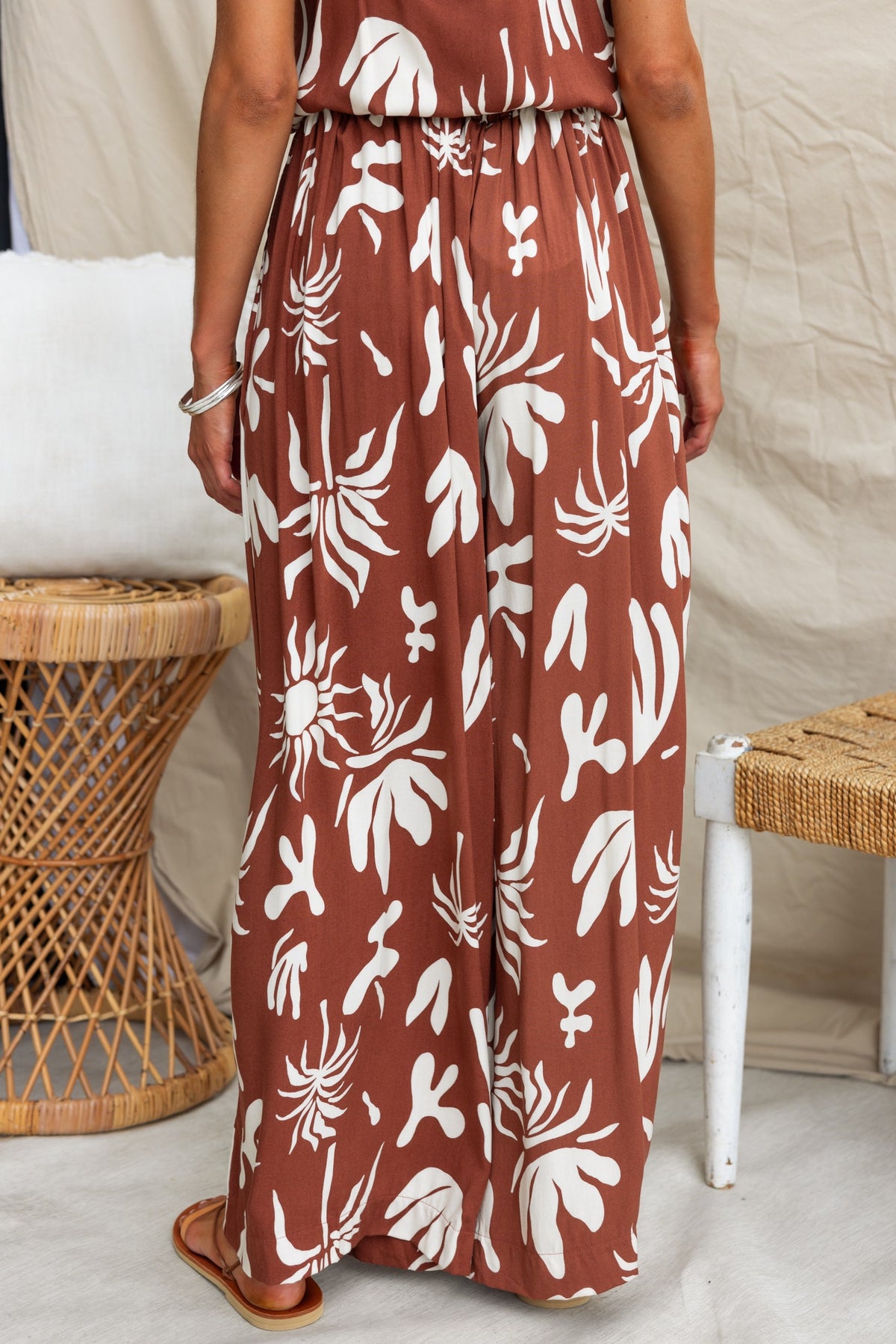Back view of model wearing Ethan Pants with abstract print in warm tones, showcasing high waist and elastic waistband.