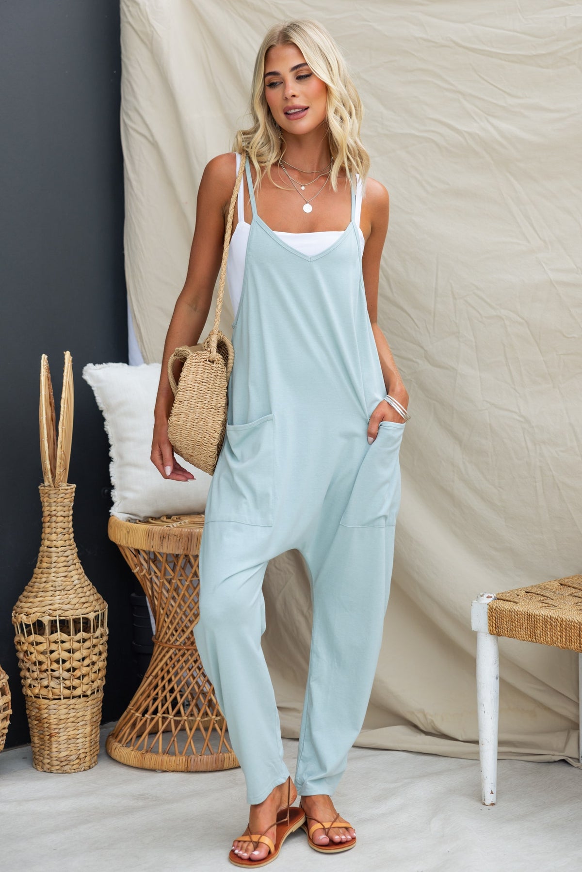 Model wearing a light blue Essie jumpsuit with adjustable straps and side pockets, styled with minimal accessories.