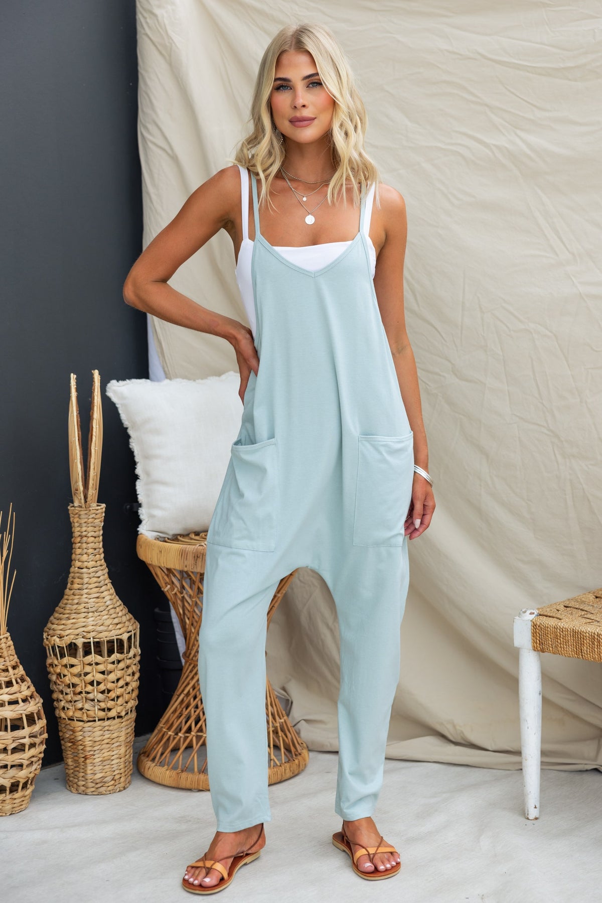 Model wearing a light blue Essie jumpsuit with adjustable straps and pockets, styled in a casual setting.