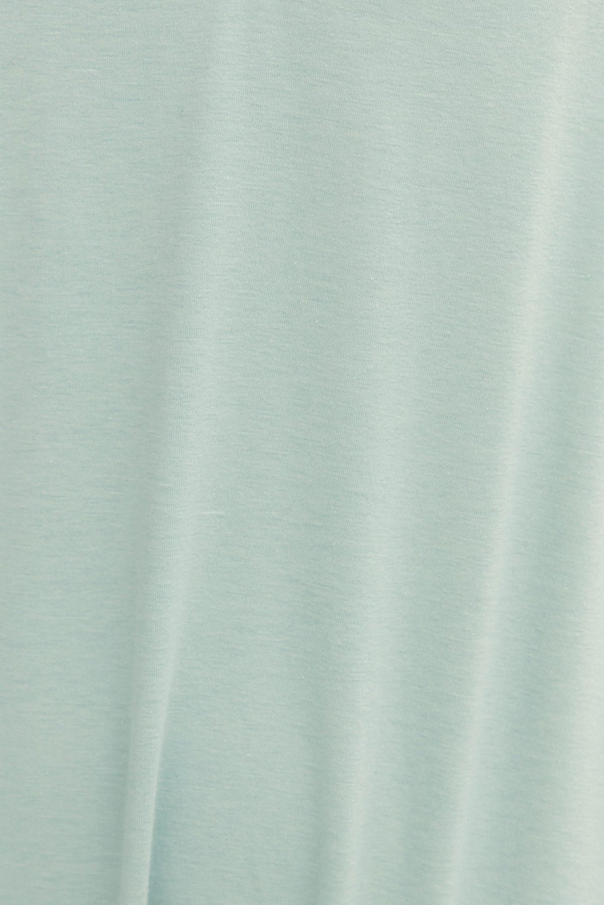 Soft mint green fabric texture of a jumpsuit, showcasing its relaxed and stretchy cotton feel.