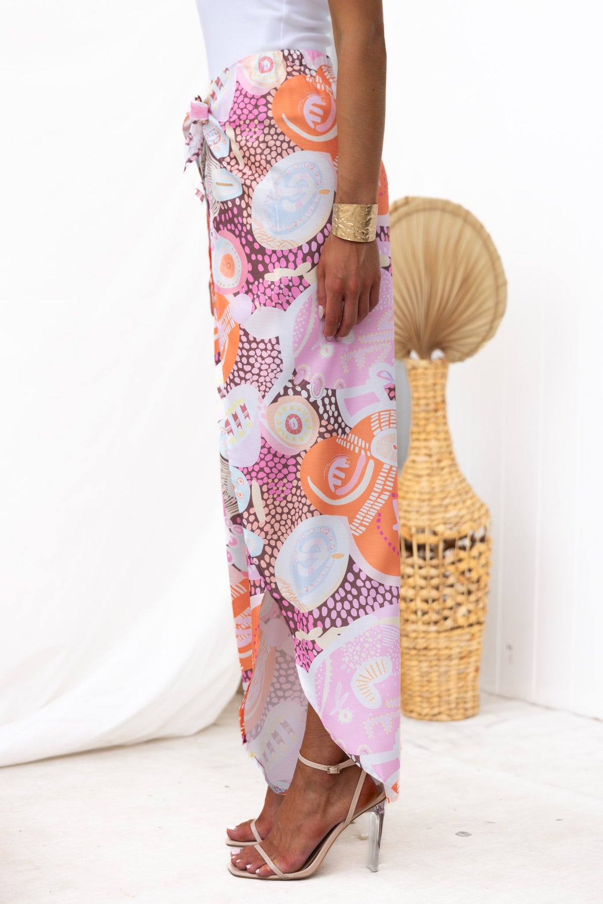Kamilla Pants with abstract print, mid-high waist and wrap tie design, featuring front splits and elastic waistband.