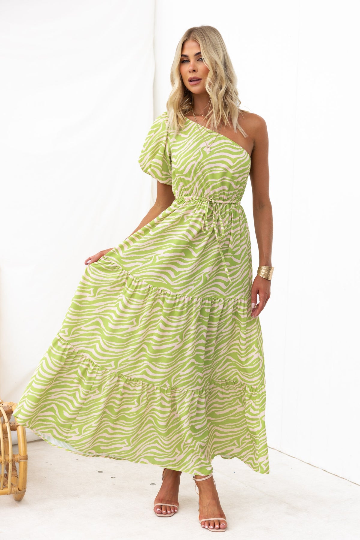 Model wearing a green animal print one-shoulder maxi dress with elastic waistband and drawstring.