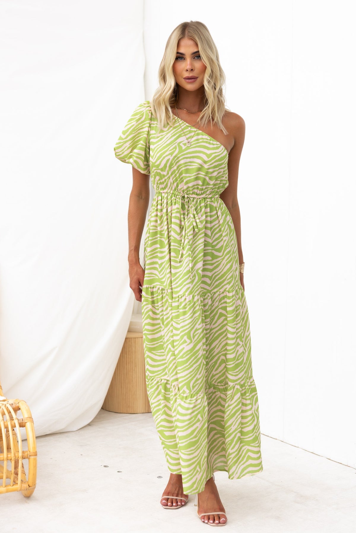 Model wearing a green animal print Hardwick maxi dress with one-shoulder neckline and drawstring waist.