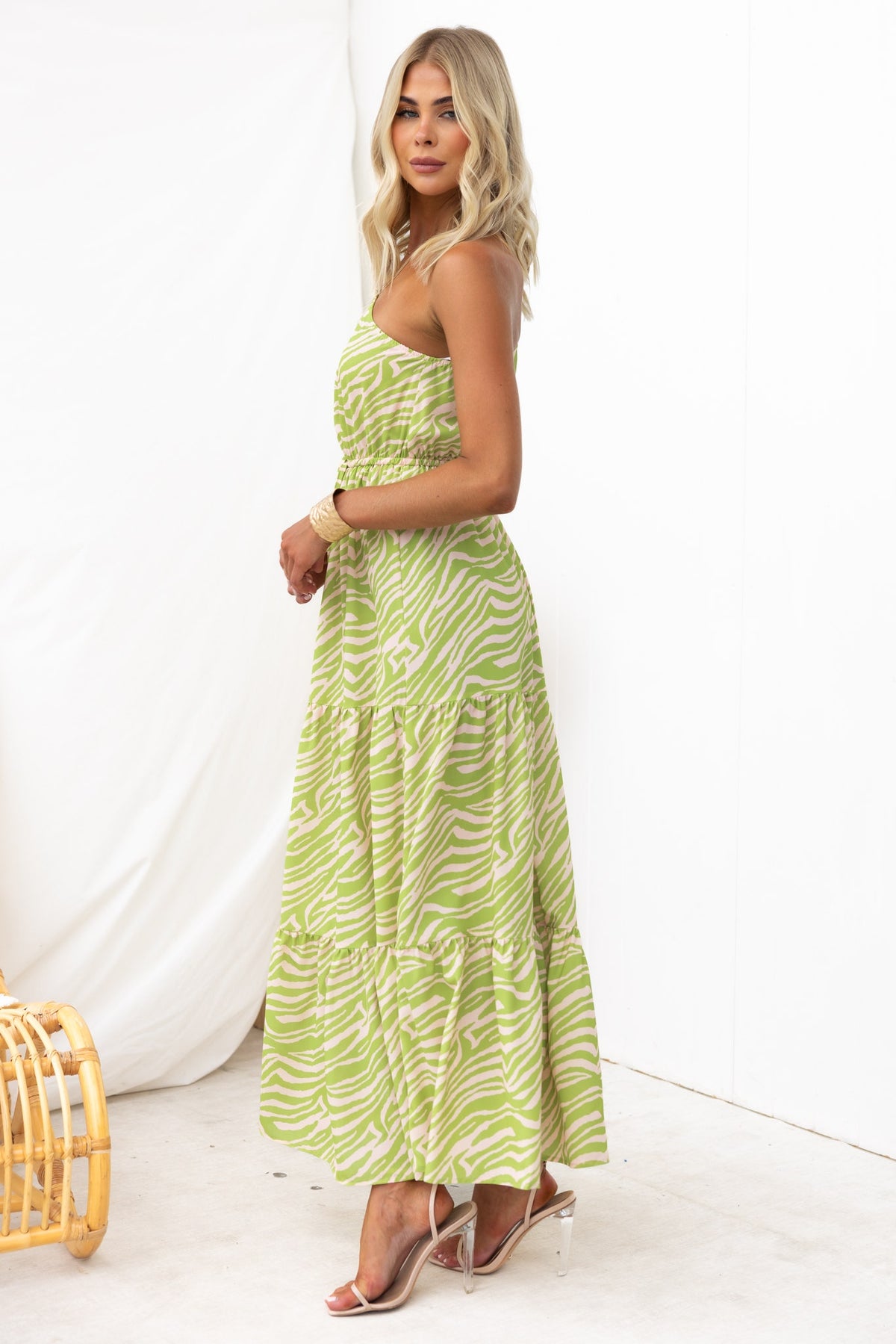 Model wearing a one-shoulder green zebra print maxi dress, featuring a drawstring waist and elastic details.