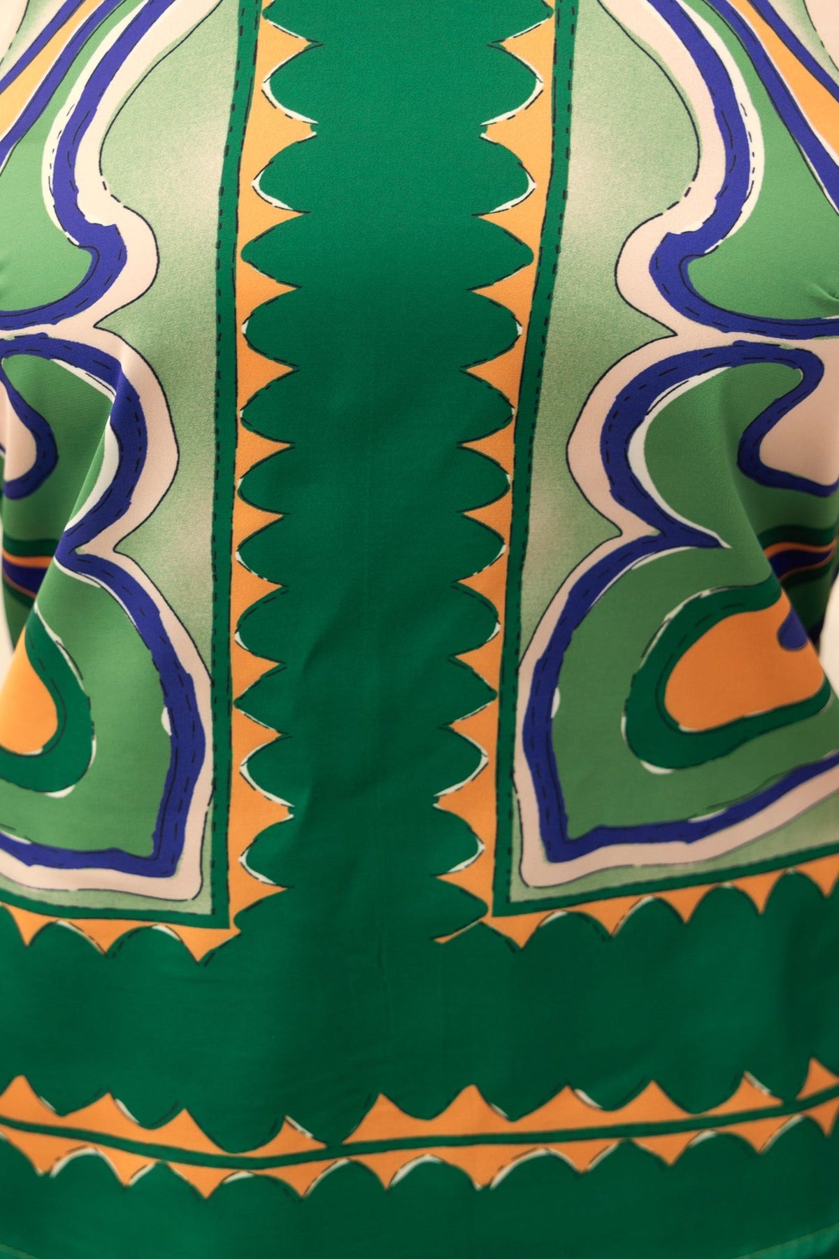 Close-up of an abstract green and orange print top with a halter neckline and intricate design details.