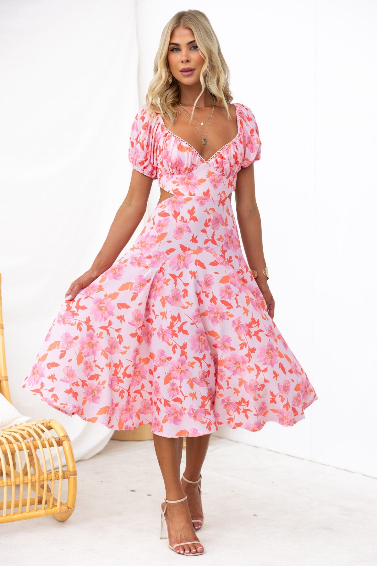 Stylish model wearing a Cupid Midi Dress with floral print, sweetheart neckline, and cut-out waist against a neutral backdrop.