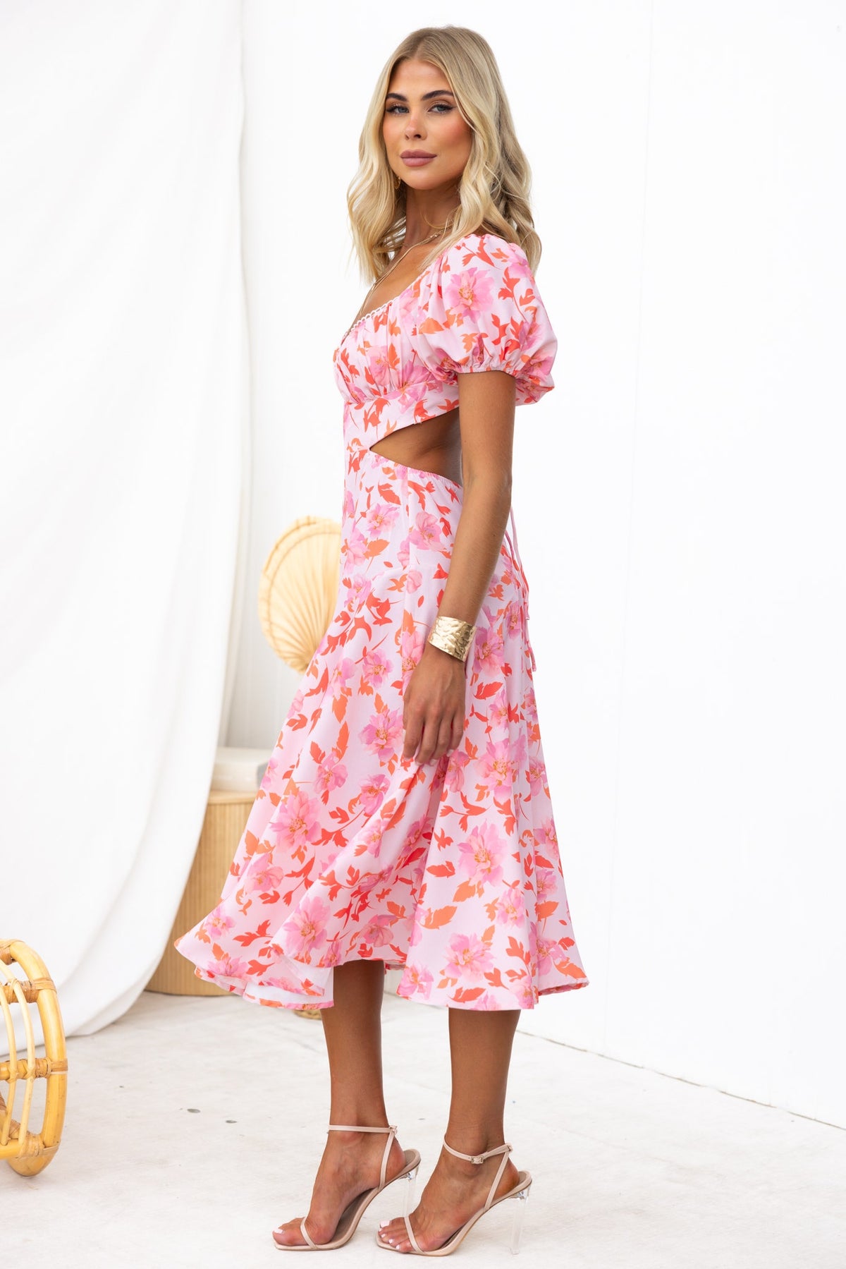 Model wearing a pink floral print Cupid Midi Dress with sweetheart neckline and cut-out at waist.