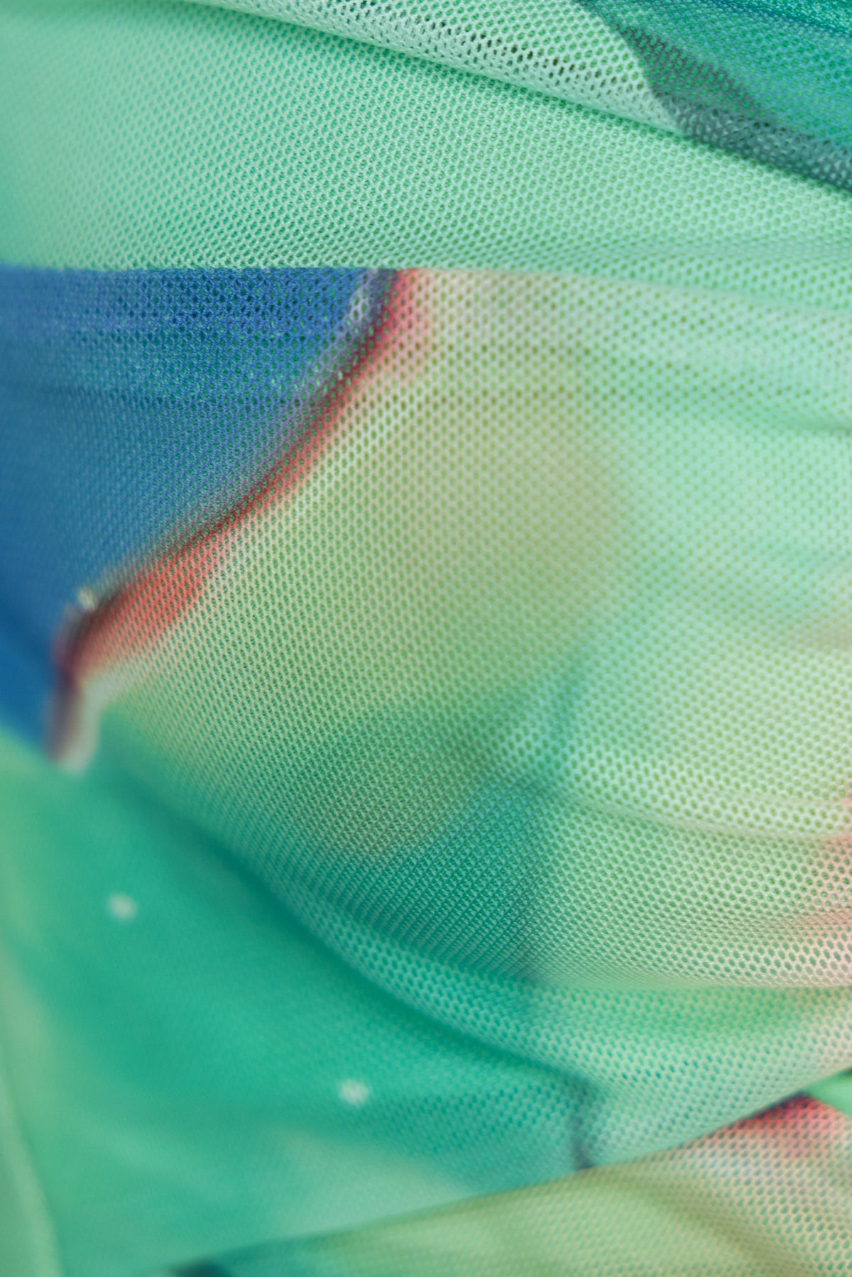 Close-up of multi-colour mesh overlay fabric, featuring vibrant greens and hints of blue in a textured design.