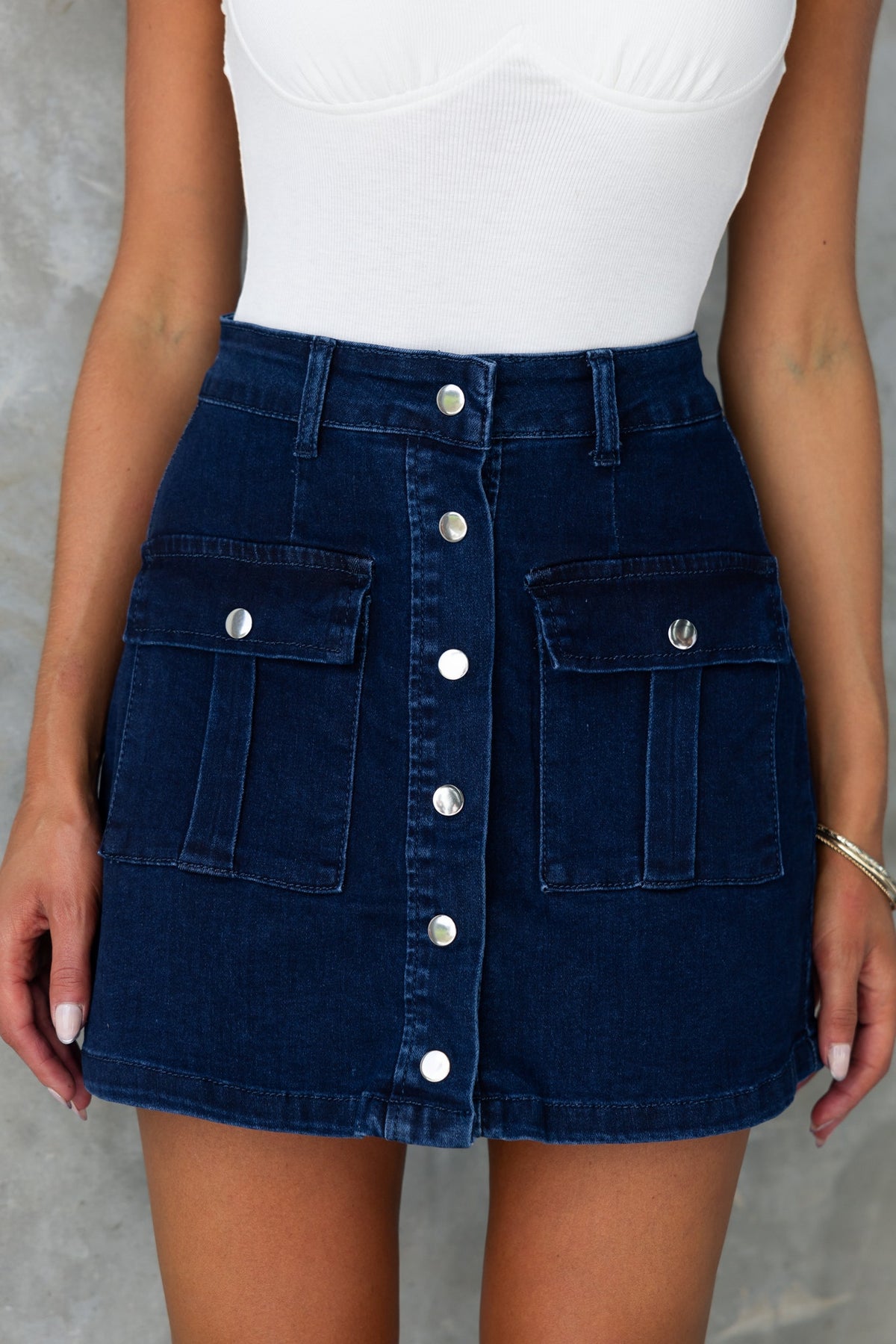 Miley Denim Skirt in dark navy with button-up front and hip pockets, styled with a fitted top.