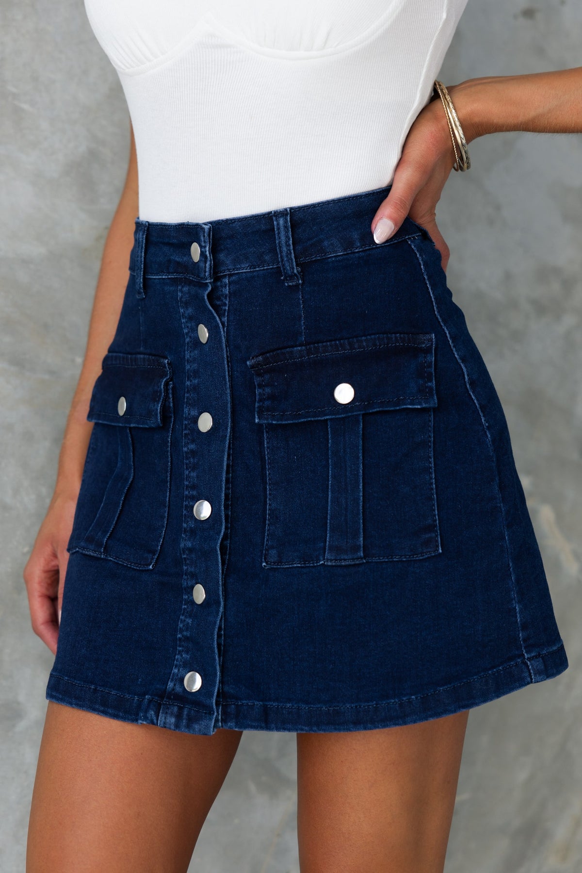 Miley Denim Skirt in dark navy, mid-high waist with button-up front and pockets, made from stretchy cotton blend.