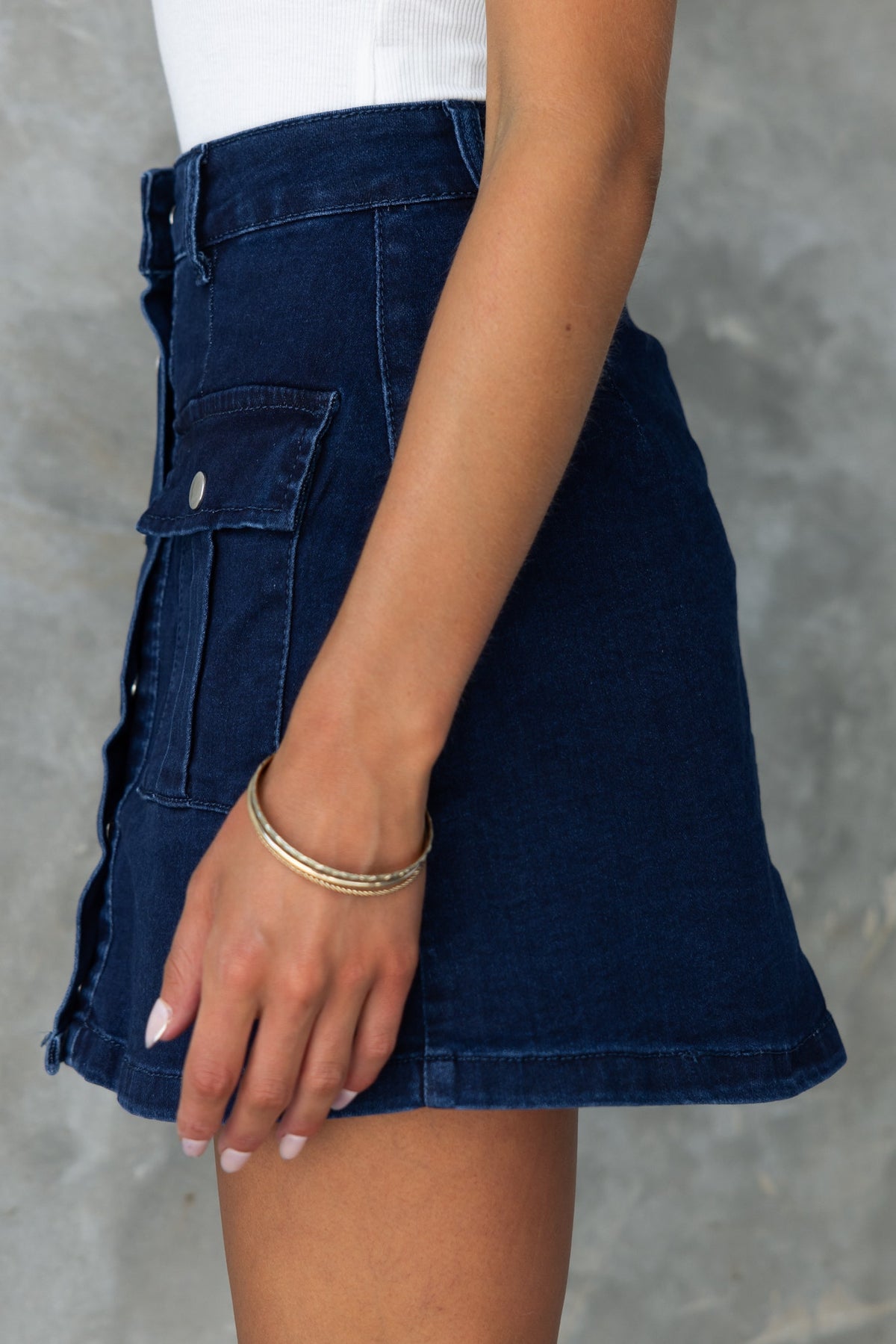 Side view of Miley Dark Navy Denim Skirt featuring a mid-high waist and button-up front, styled with a casual top.