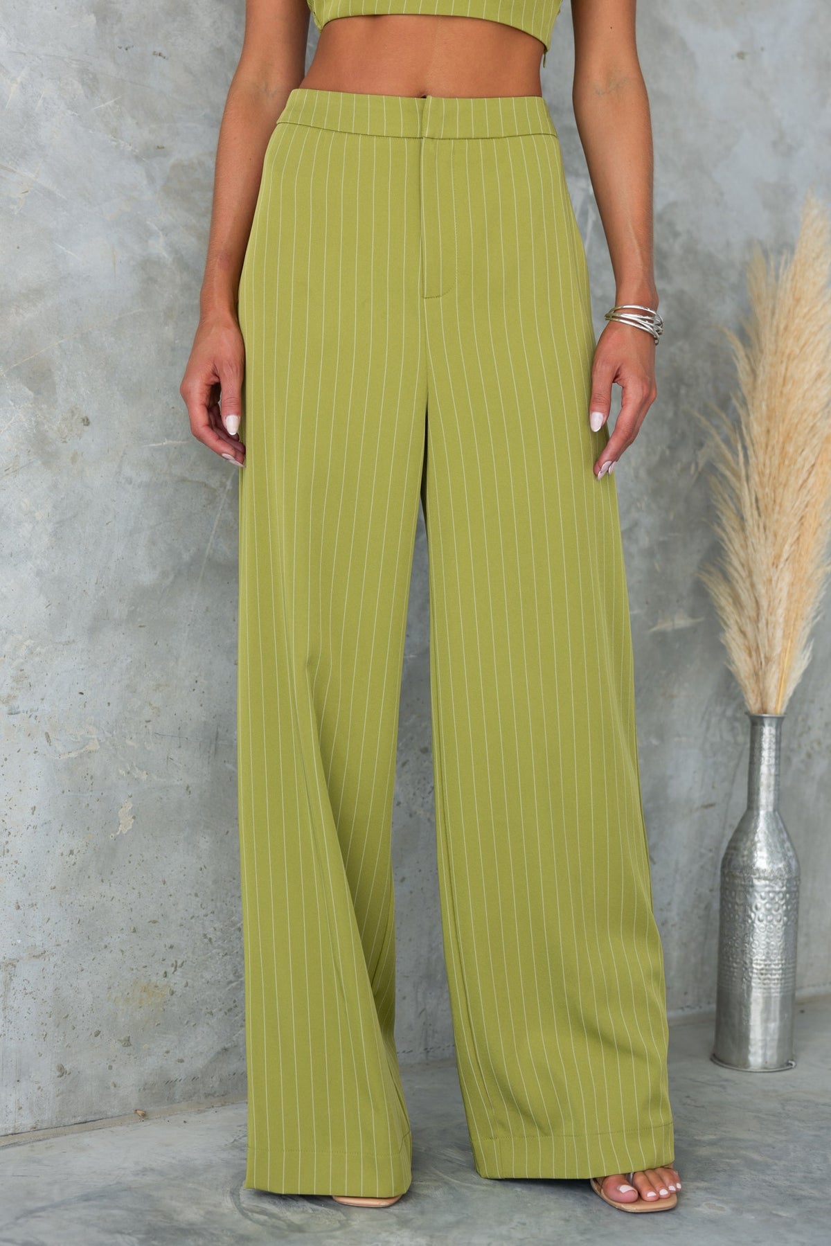 Silvia Pants in olive green with vertical stripes, mid-high waist fit, styled with a crop top.