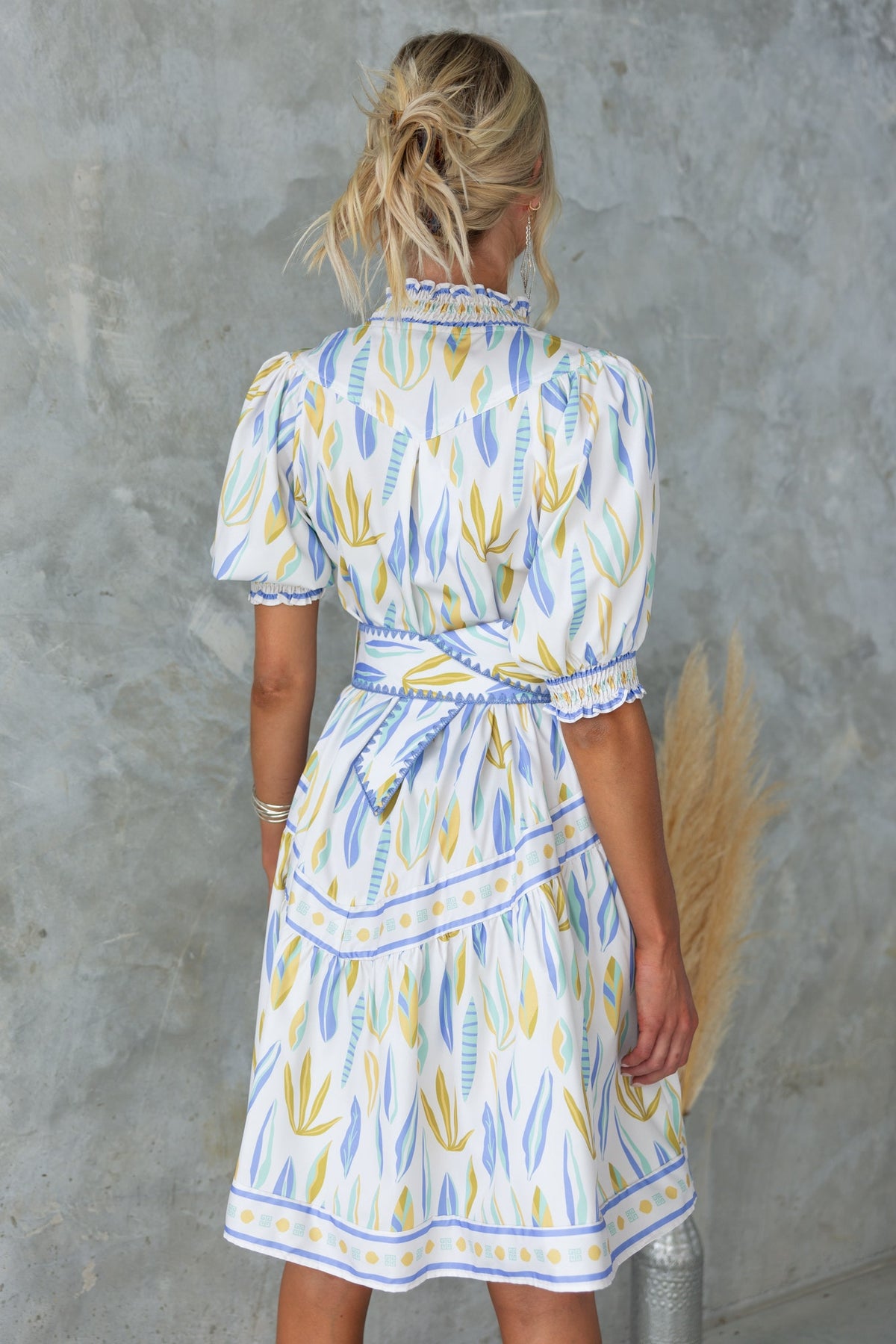 Back view of Kalmia Dress featuring floral print, puff sleeves, and a removable belt.