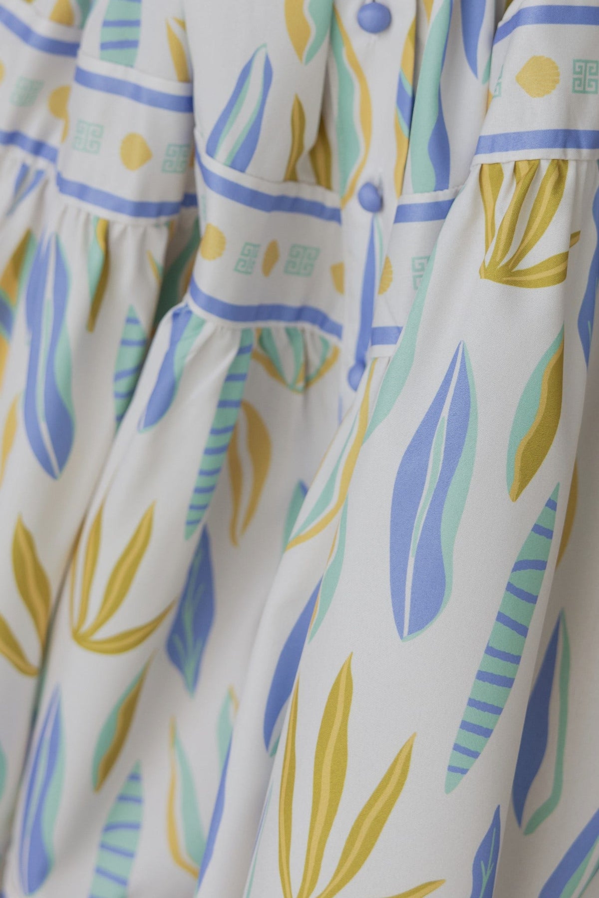 Close-up of Kalmia Dress featuring floral prints, high neckline, and button-up front with elastic details.