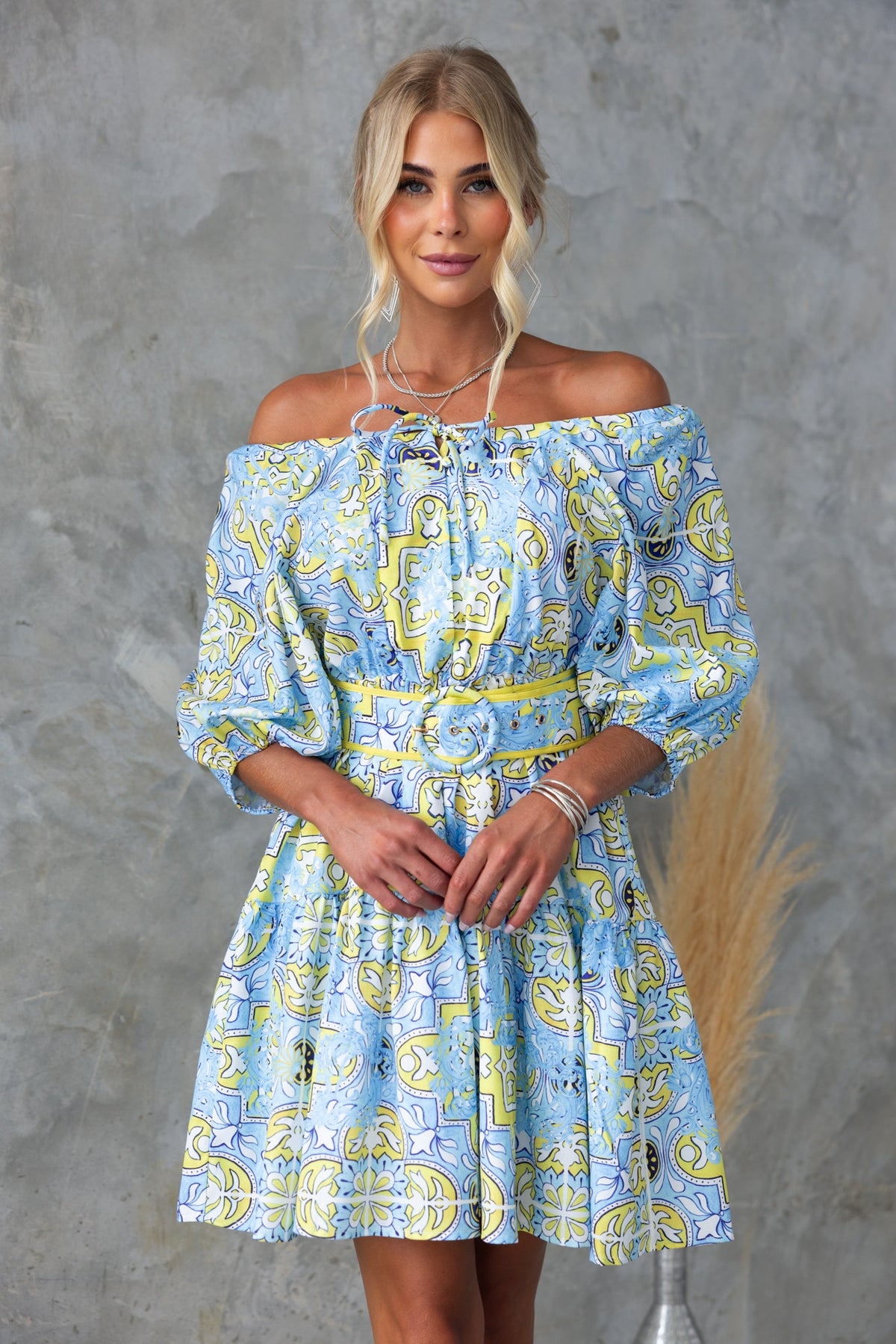 Model wearing Stelle Dress with abstract print and adjustable tie neckline, showcasing a vibrant blue and yellow pattern.